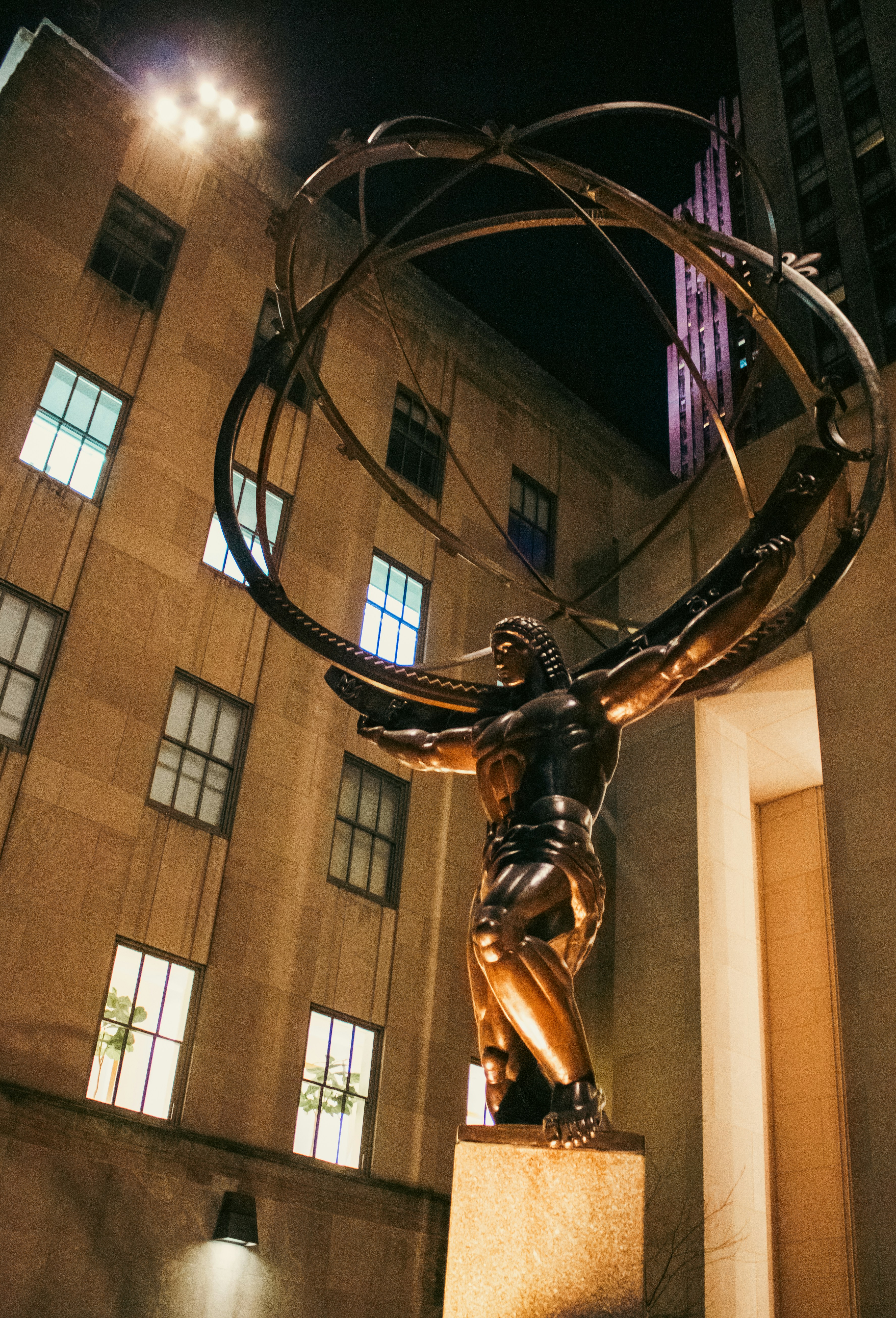 Die Atlas-Statue ragt nachts hoch in die Höhe.