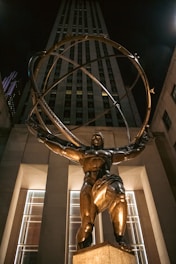 Atlas statue holds the globe in front of a skyscraper.
