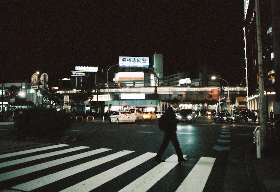 A person crosses a street at night., CineStill 400 Dynamic Color