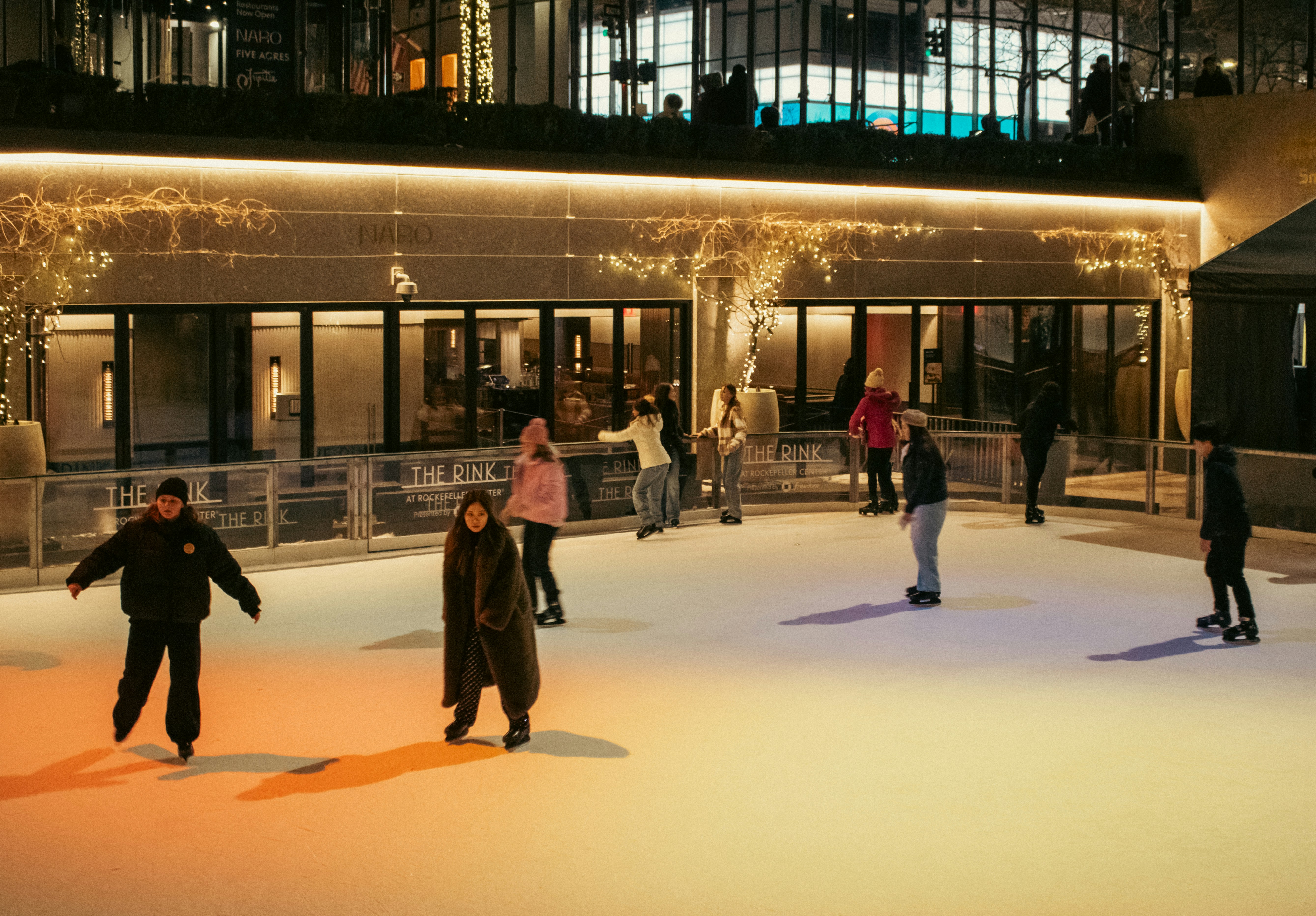 People ice skating outdoors at night.