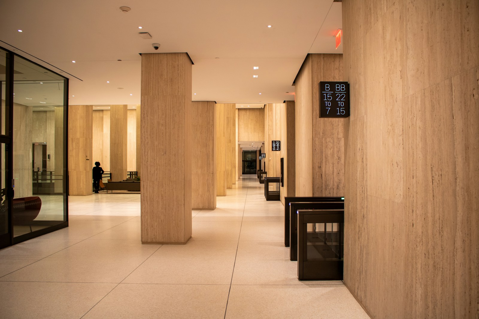 Office building lobby with travertine-clad columns over a large-format stone floor