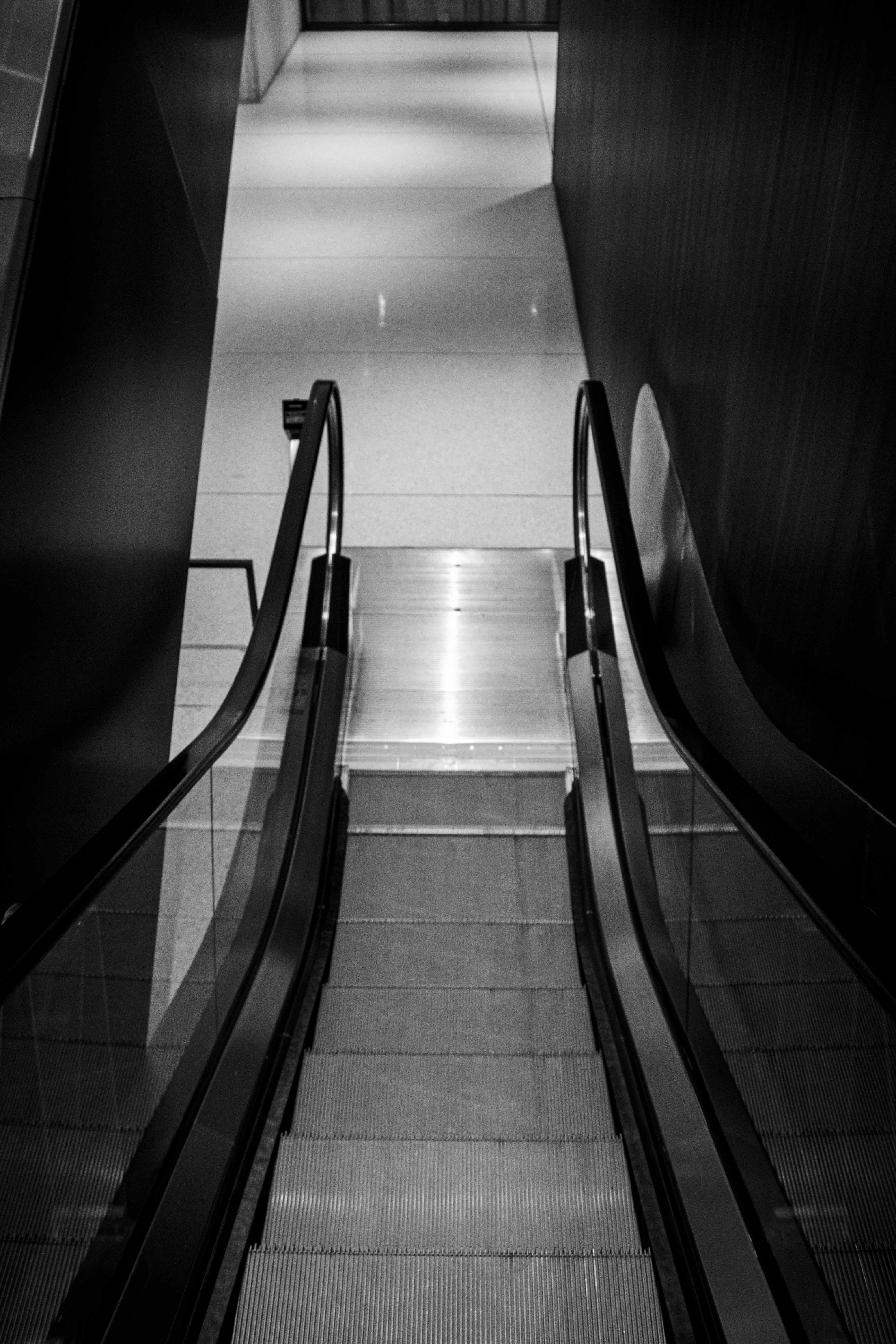 Escalator descends into a bright hallway.