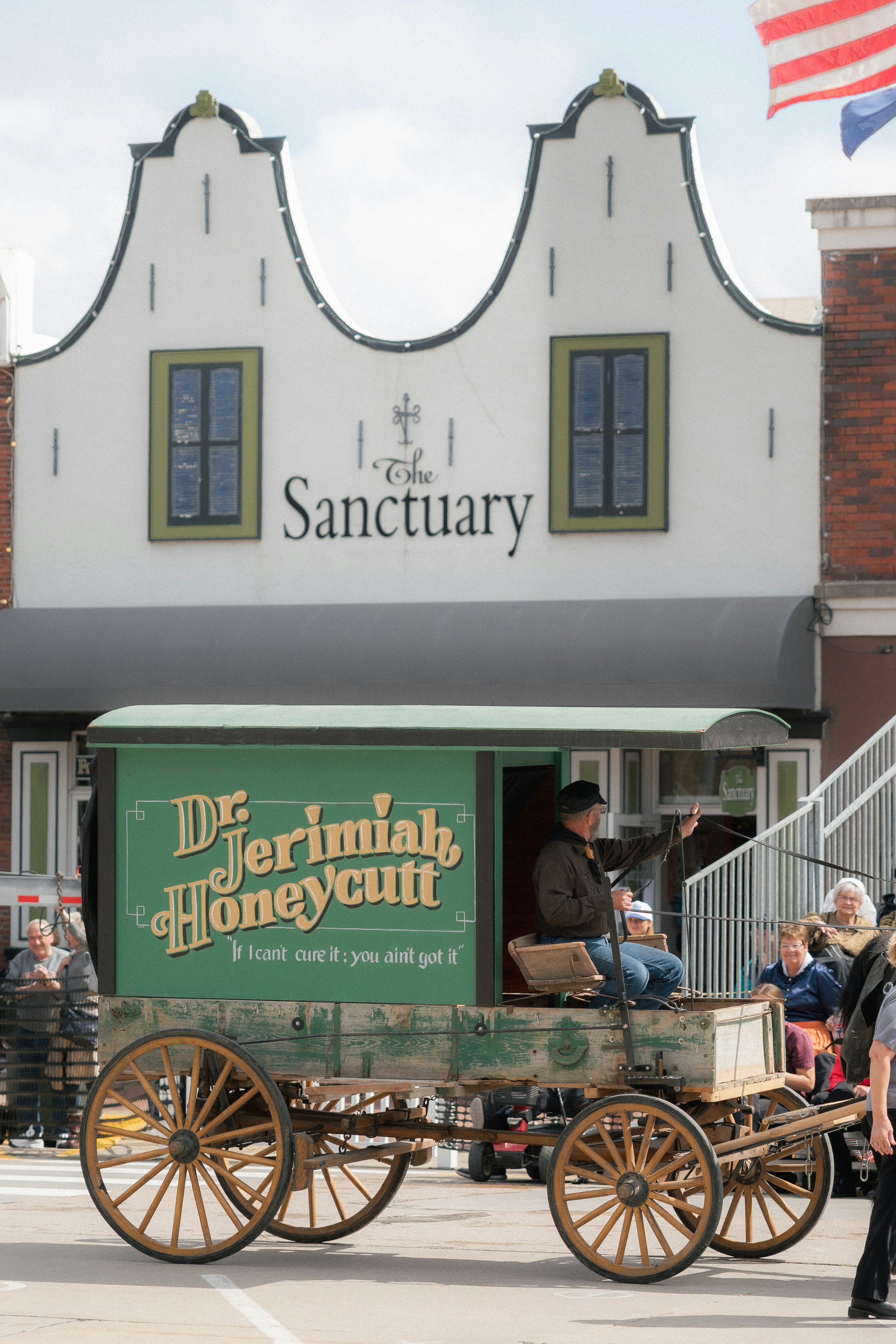 A vintage wagon drives past a building.