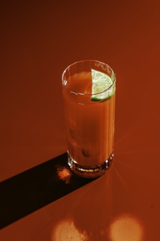 Red cocktail with lime on a red surface.