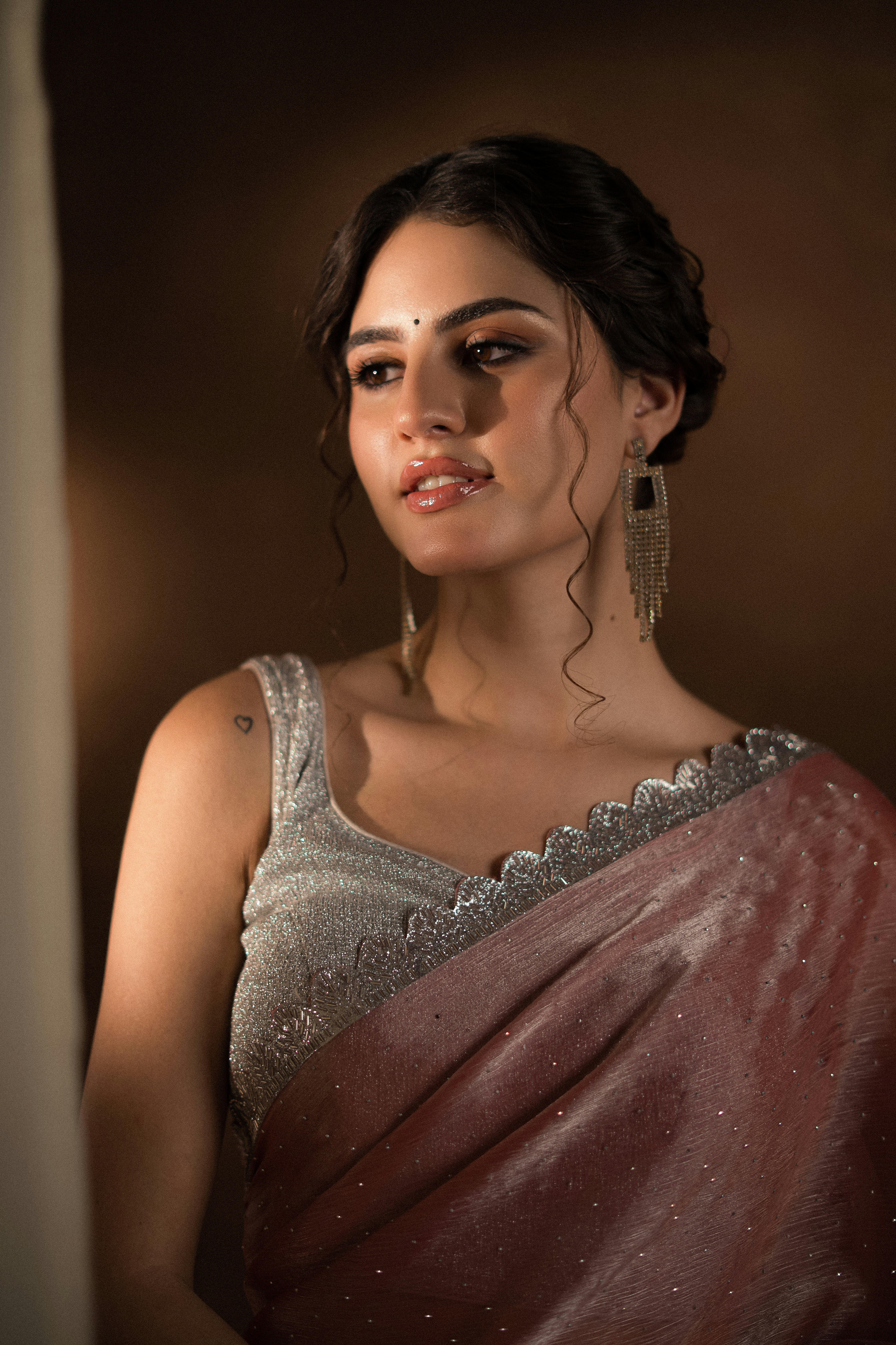 Eine Frau posiert anmutig in einem schimmernden Sari.