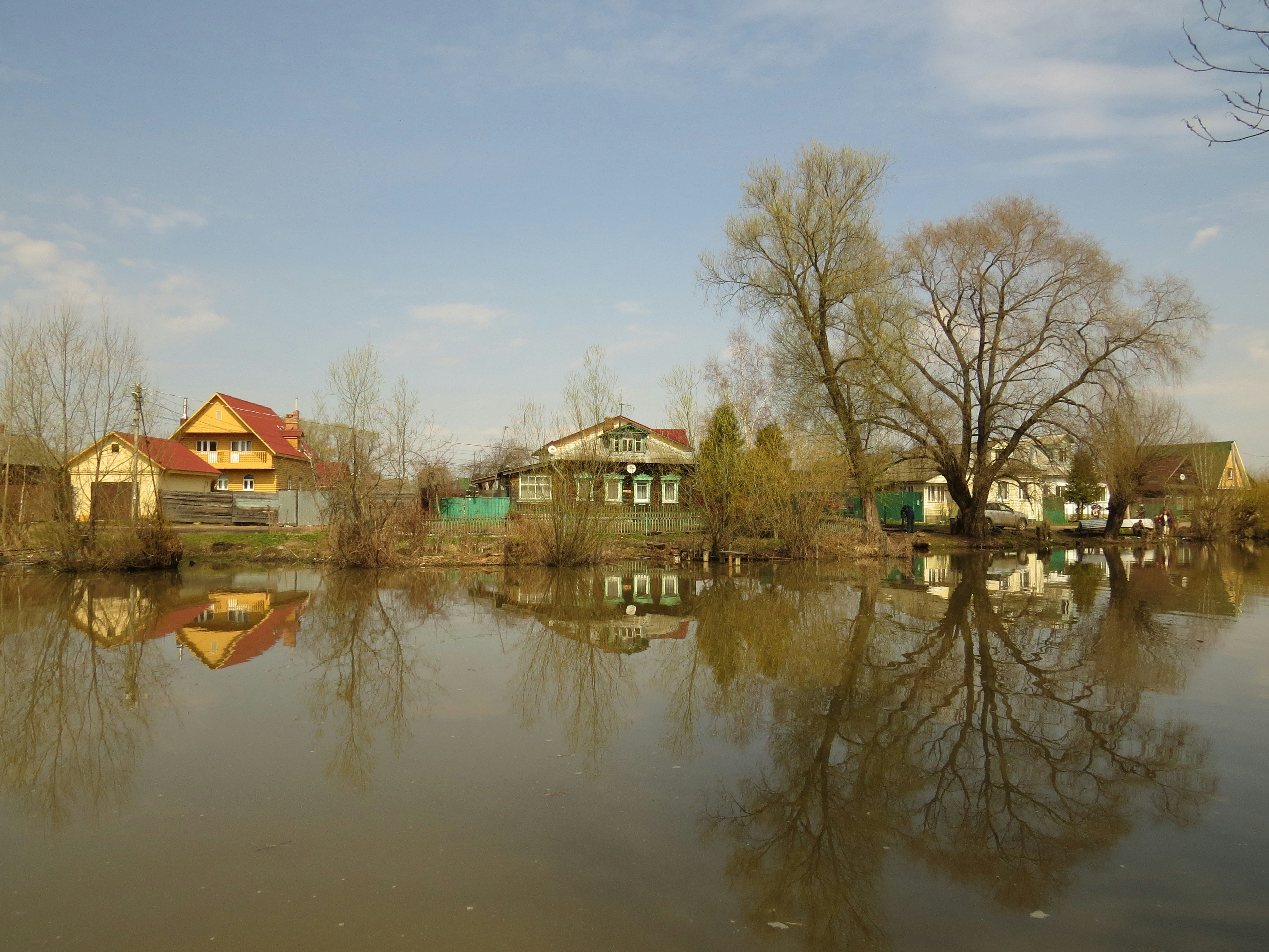 Houses reflect in still water.