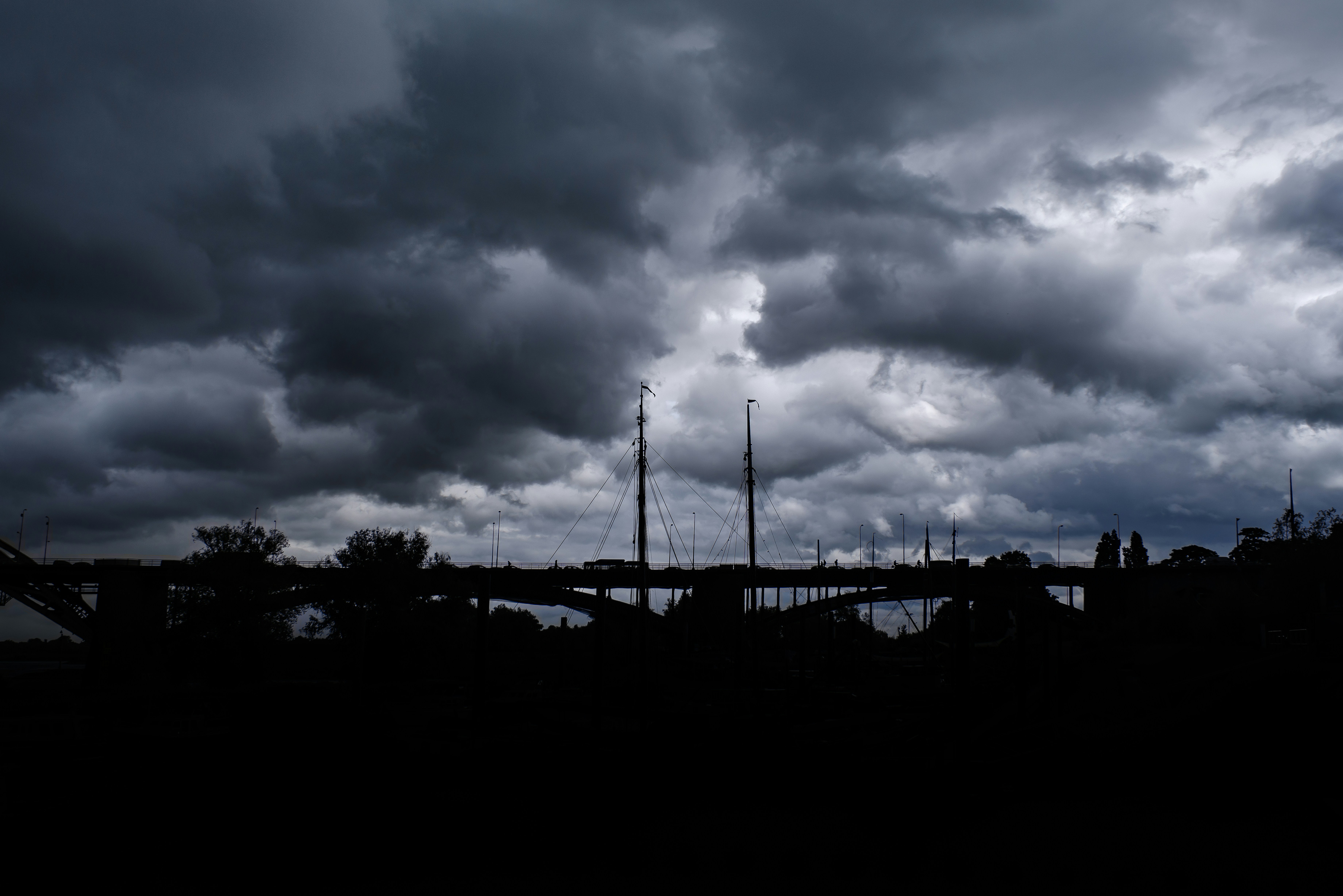 Dark, ominous clouds hover over a bridge.