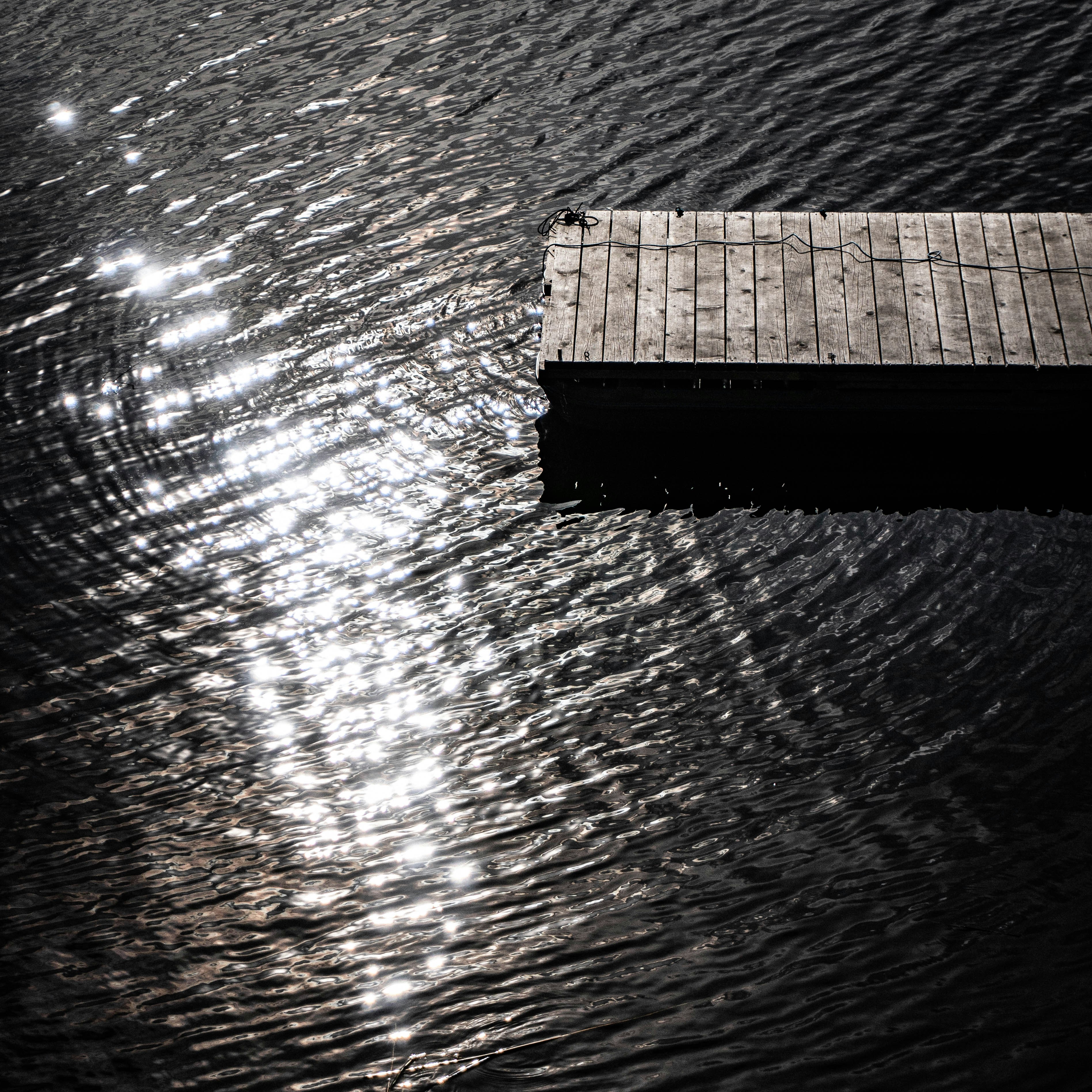 Wooden dock sits beside glistening water.