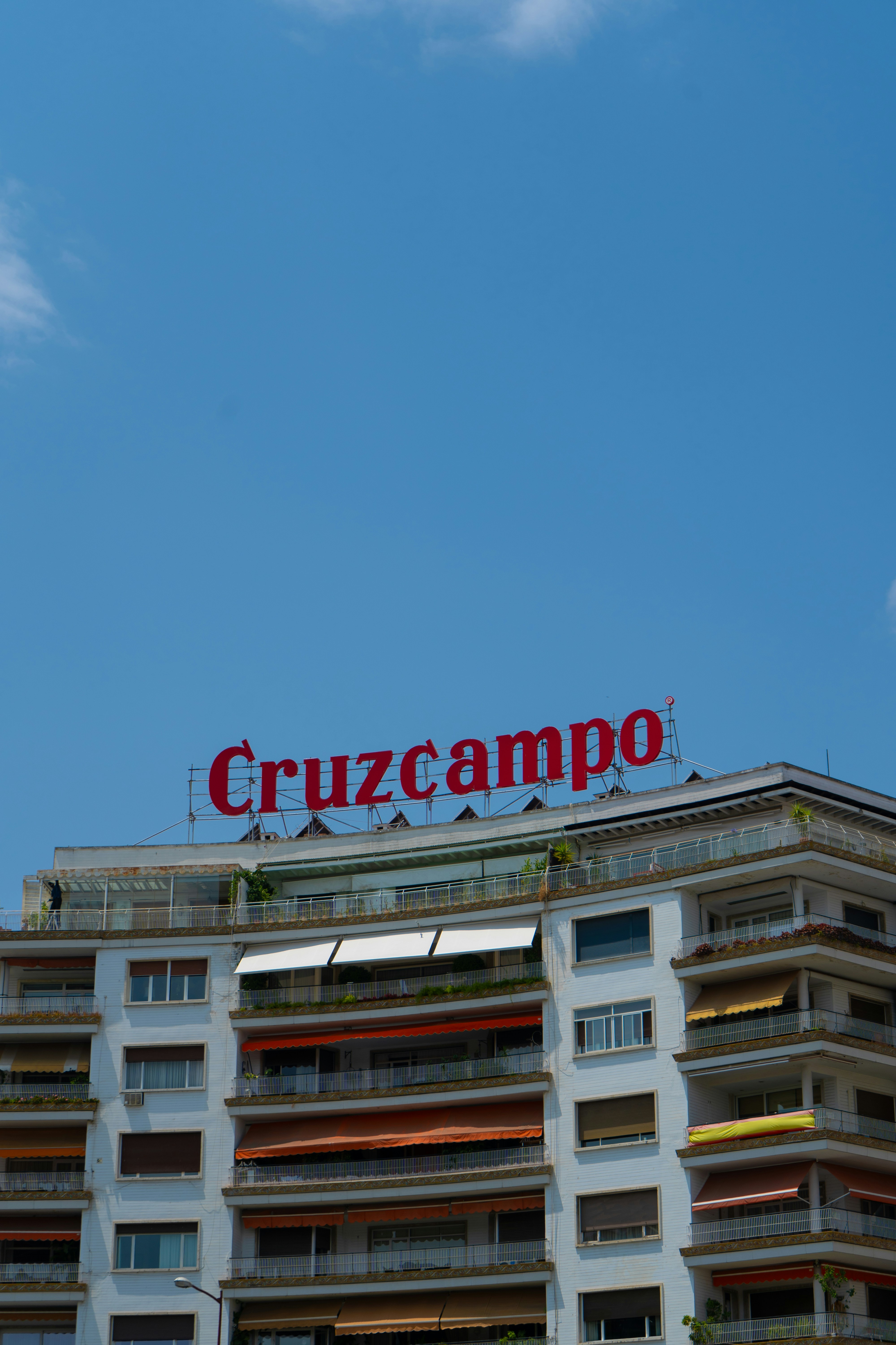 Letrero de Cruzcampo en un edificio bajo un cielo azul.
