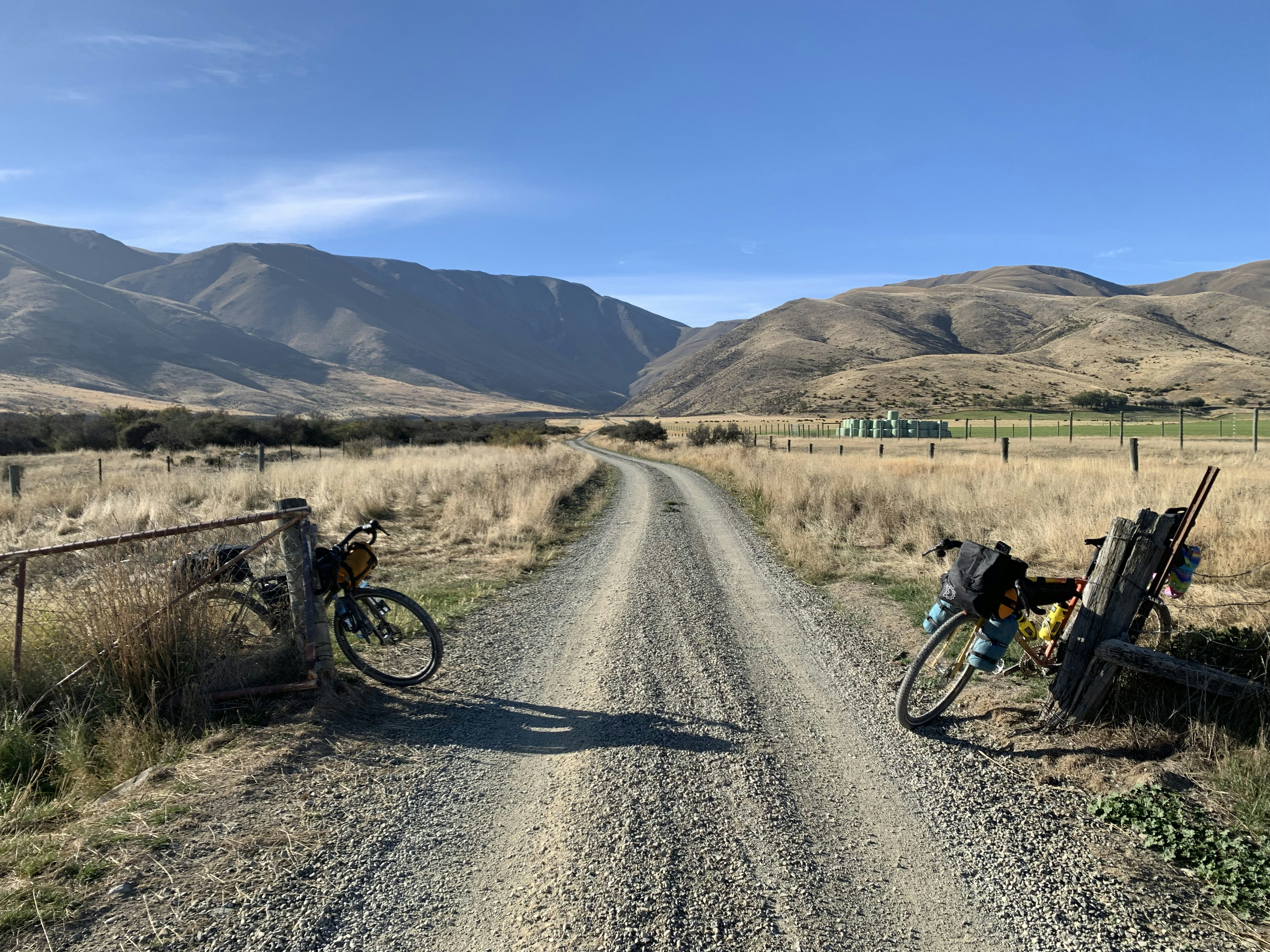 Bikes rest beside gravel road in a valley.