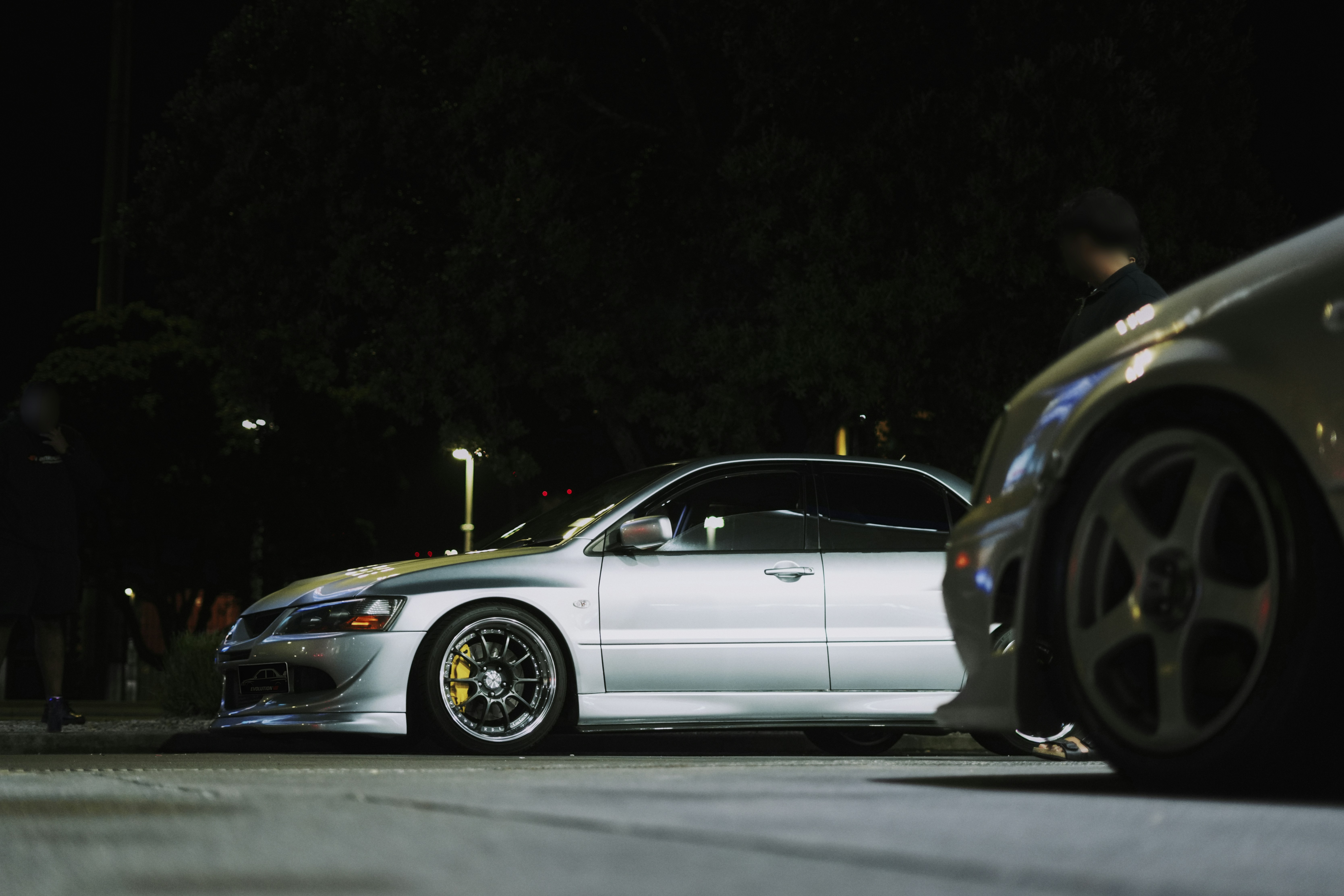 Silver cars are parked at night.