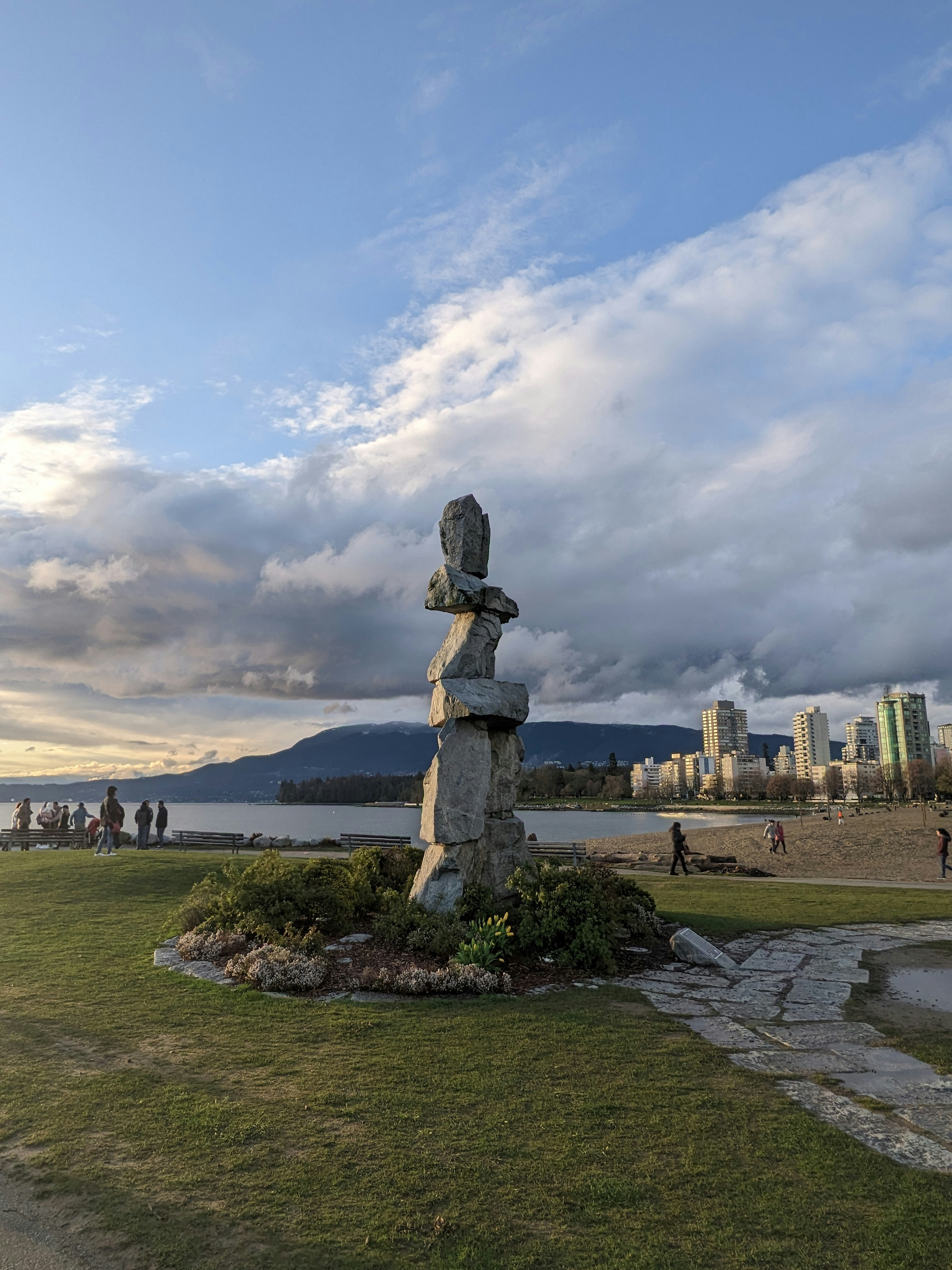 An inukshuk sculpture stands near the ocean.