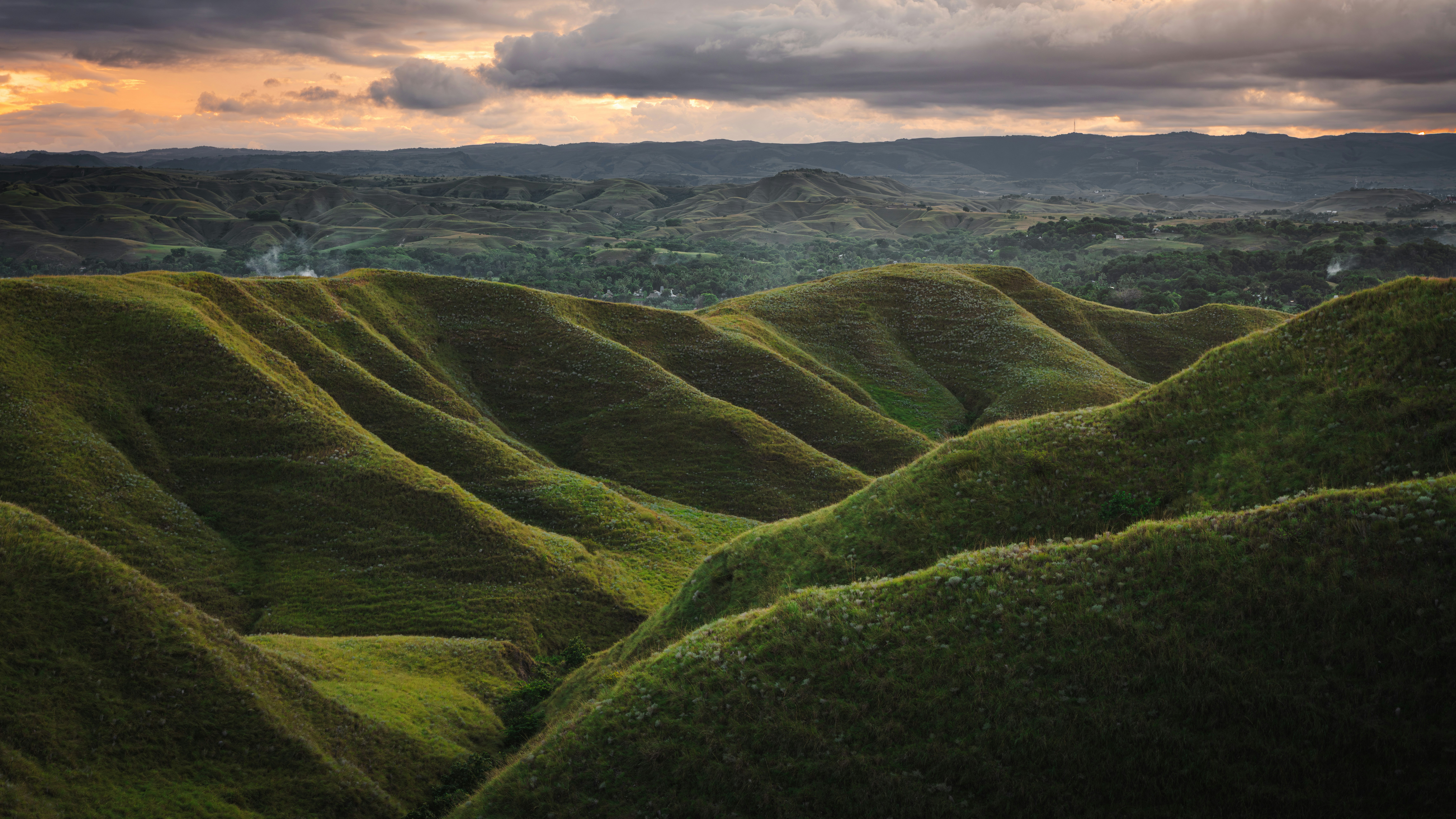 Rolling green hills under a dramatic sky.
