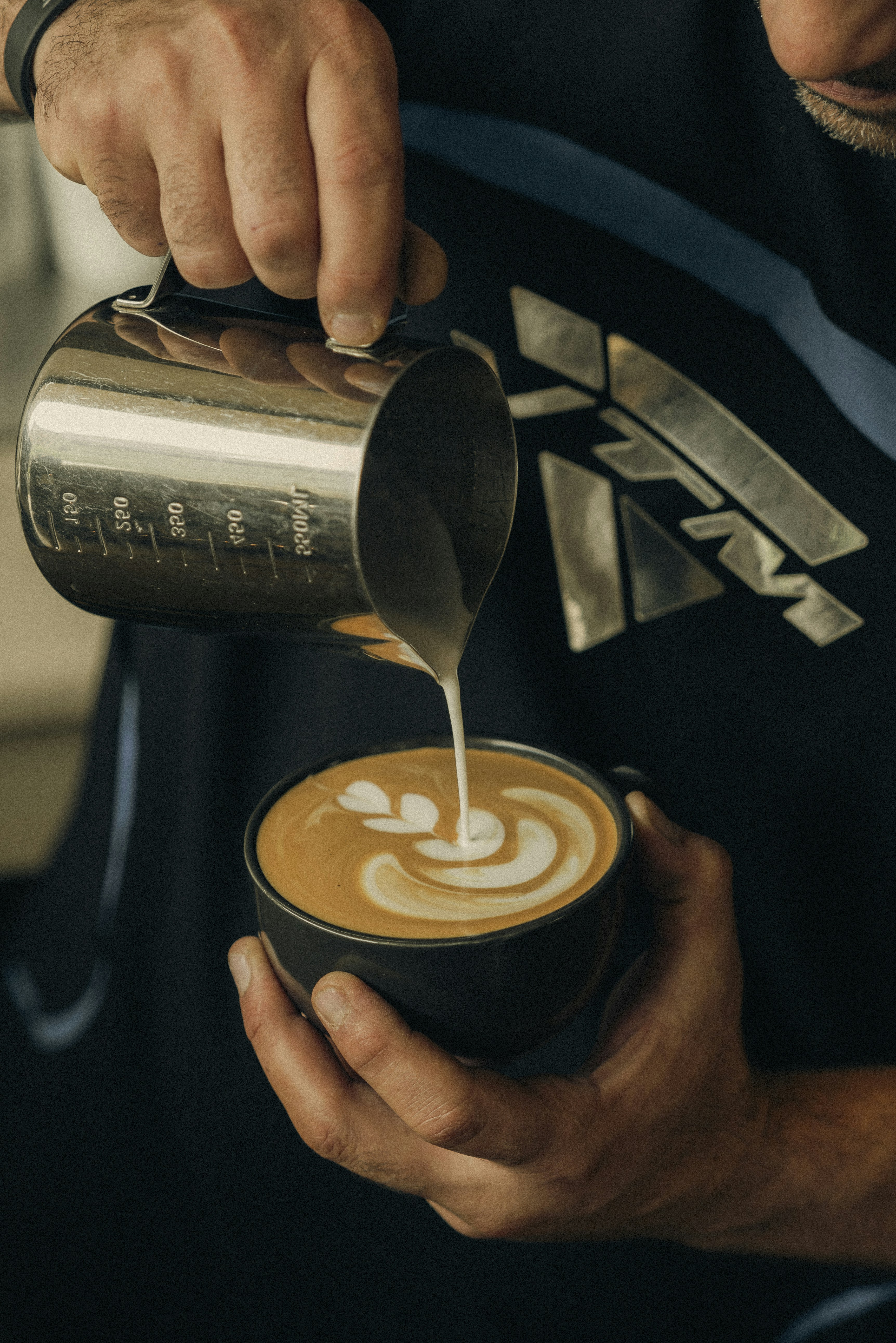 Barista pours milk to create latte art.