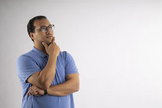 Man with glasses is deep in thought.