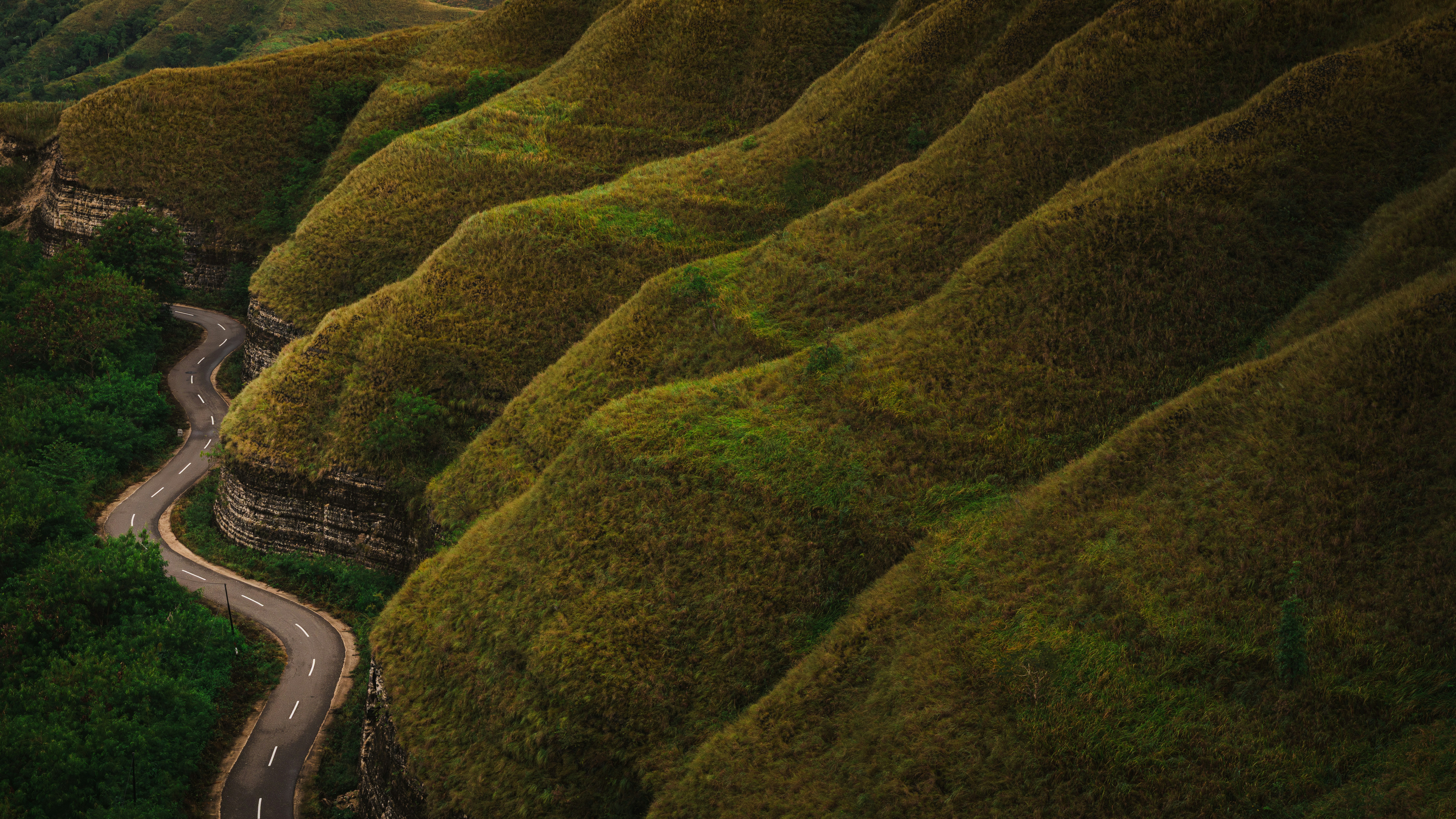 A winding road carves through rolling, green hills.
