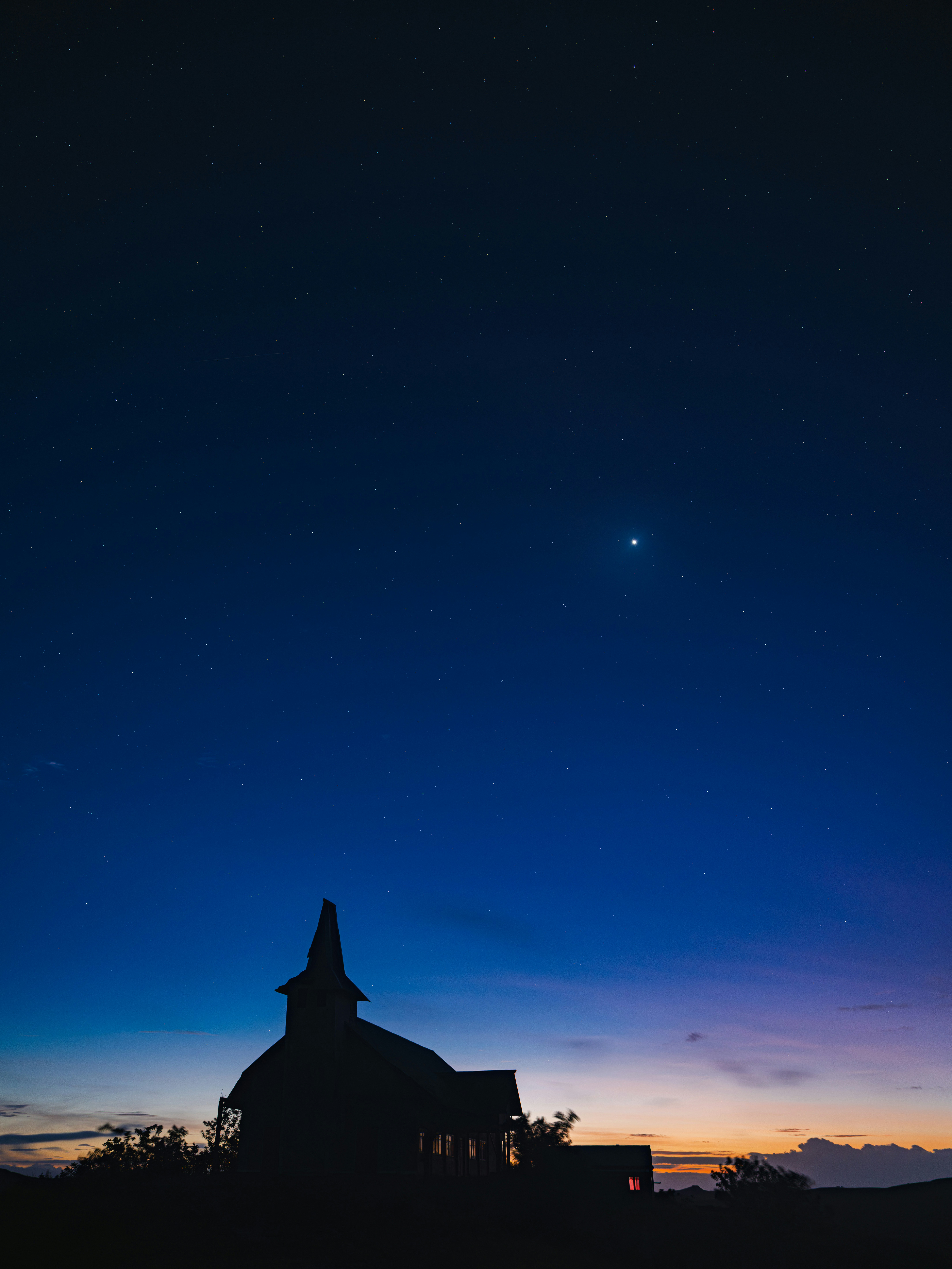 Church silhouette stands under a starry night sky.