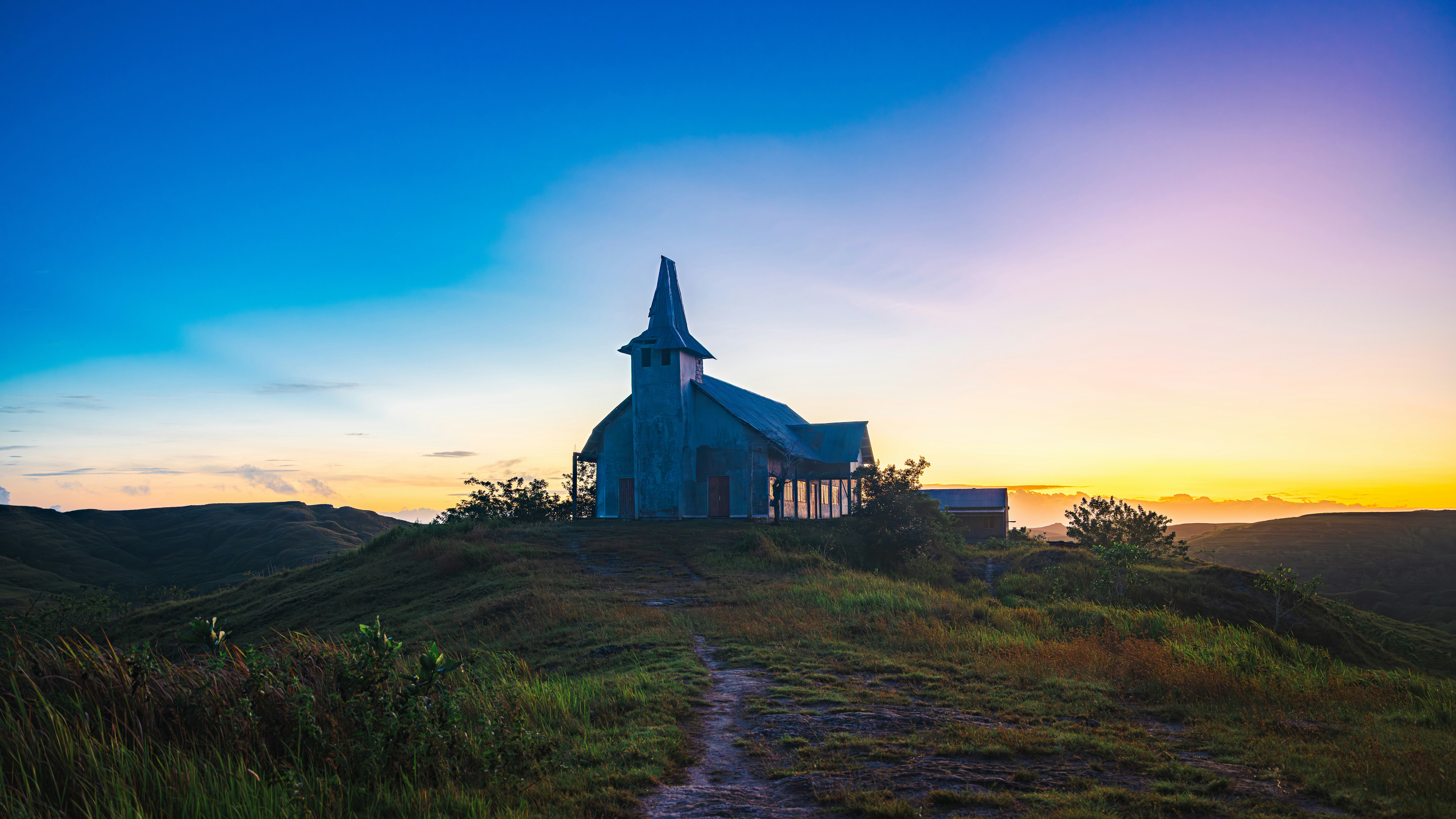 A church sits upon a hill at sunrise.