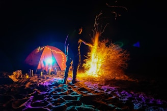 A person is camping by a bright campfire.