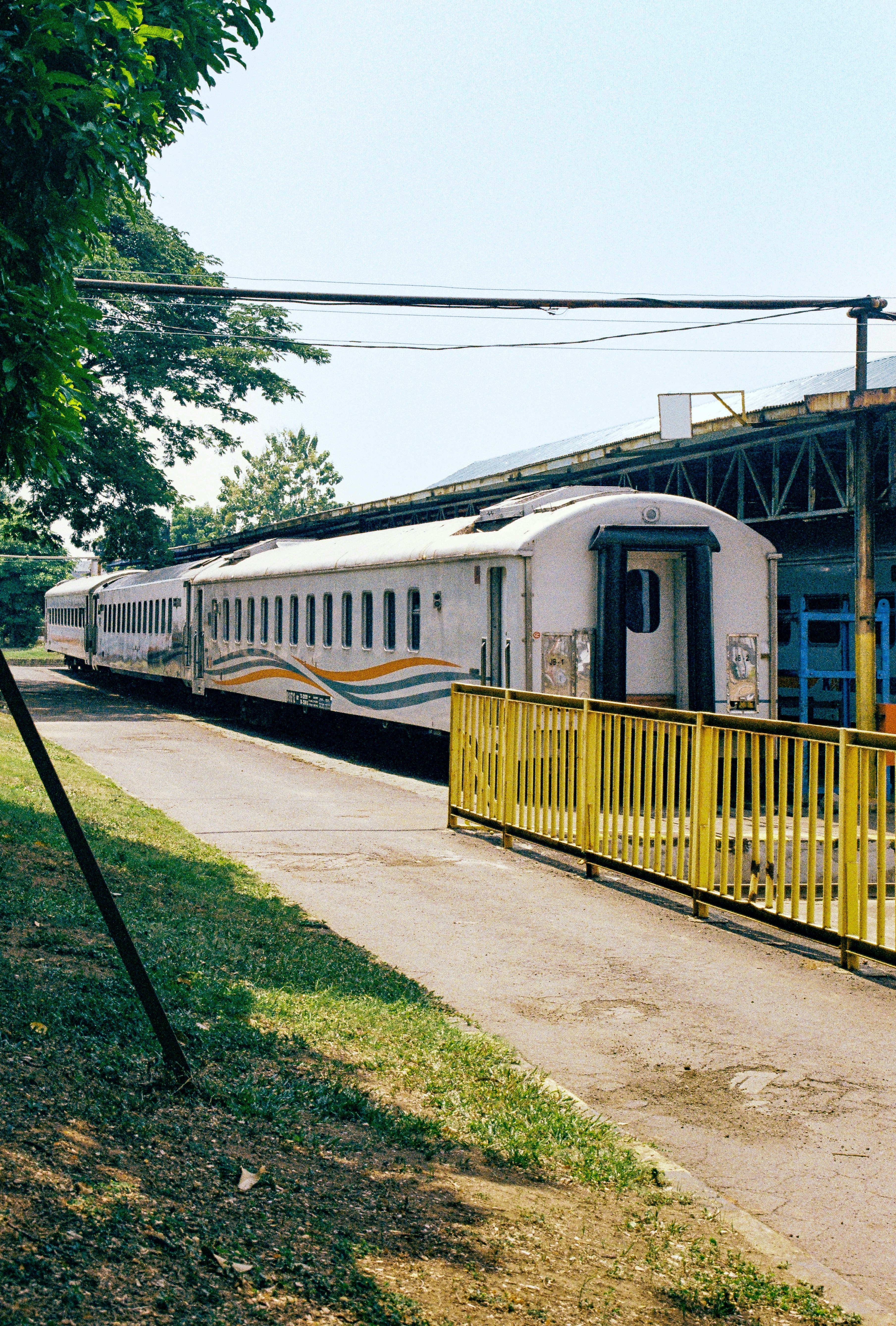 A train is parked near a yellow fence.