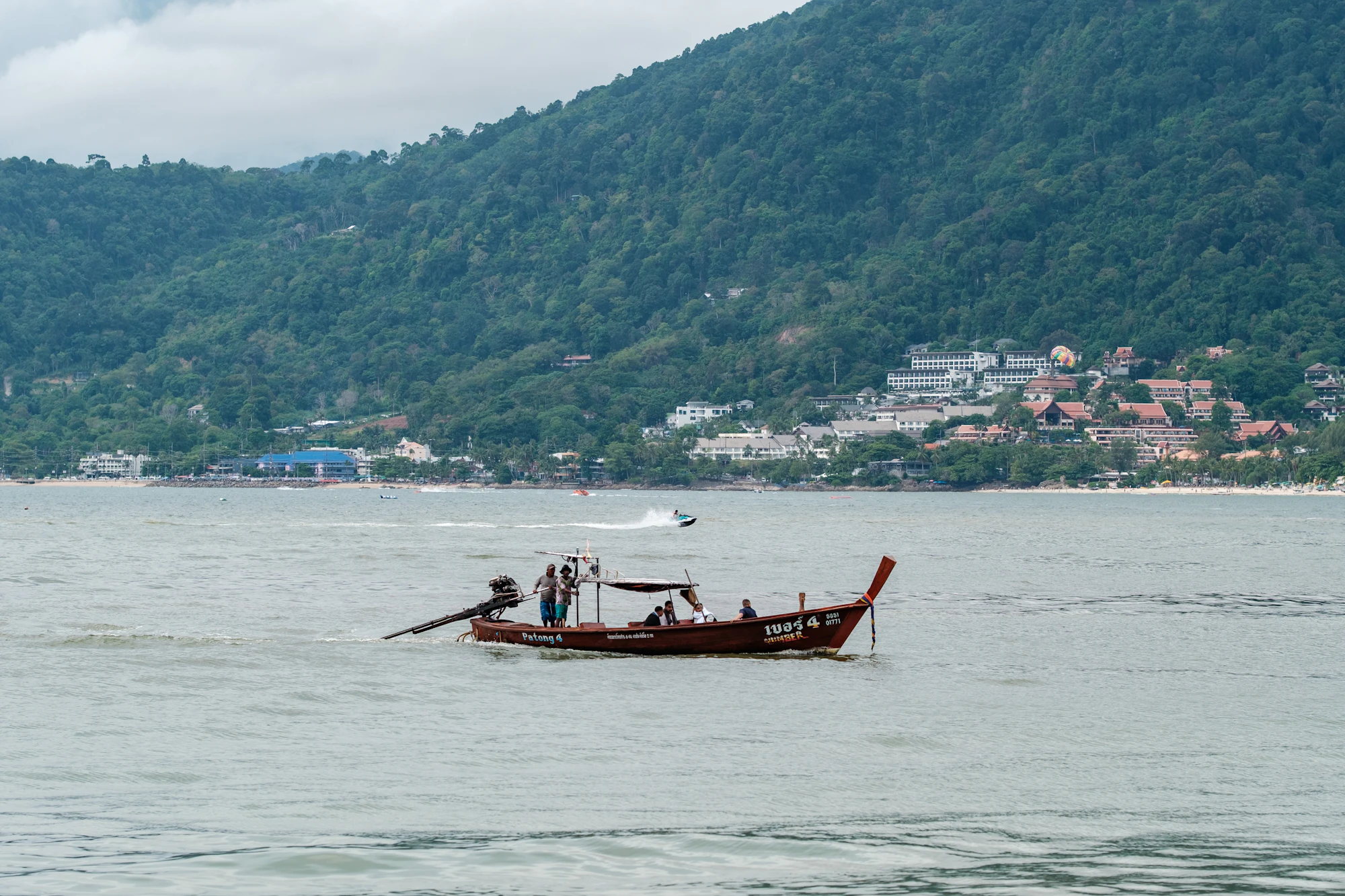 A longtail boat on Patong Bay below the green hills of Patong