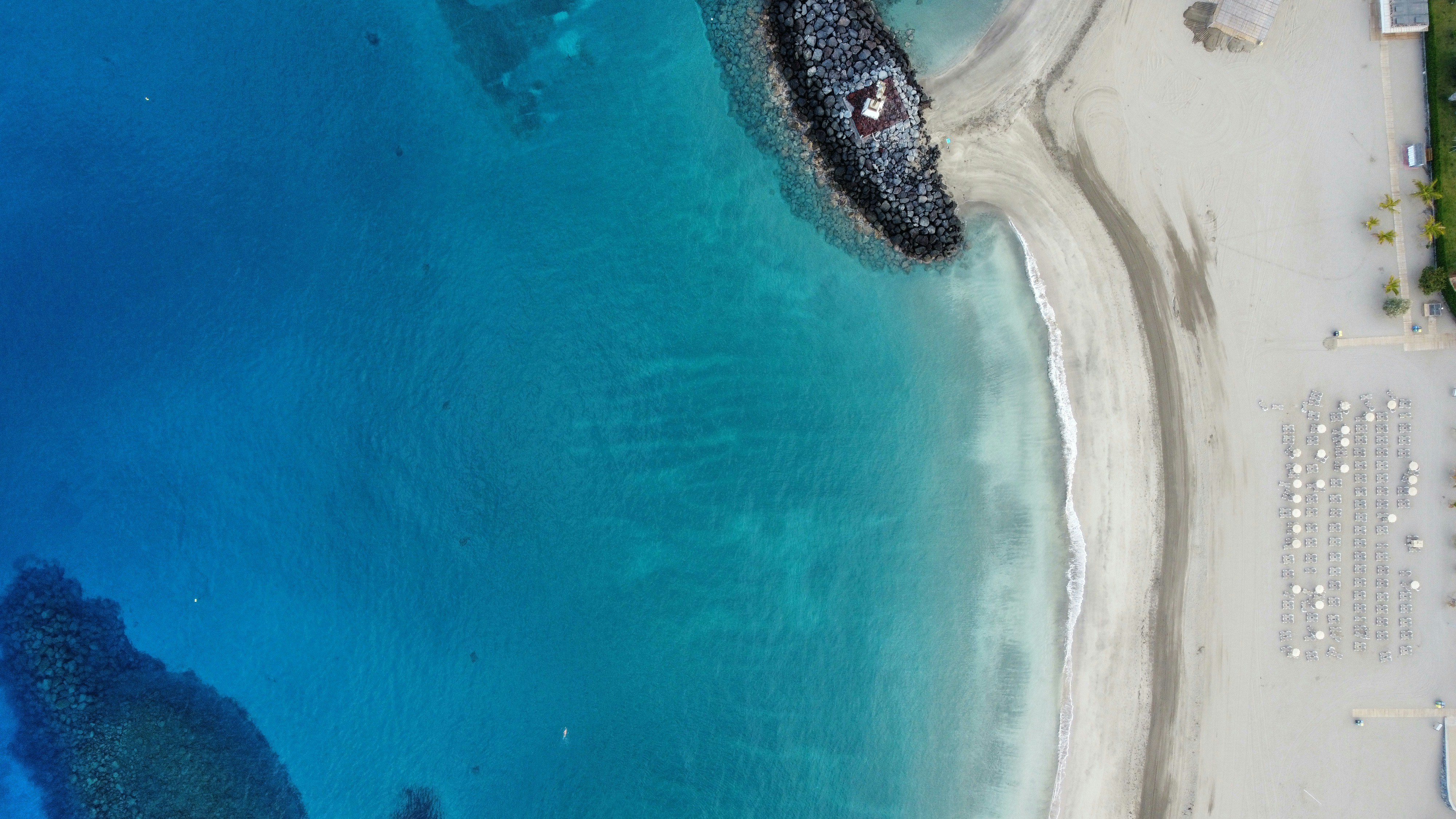 Aerial view of a sandy beach with clear blue water