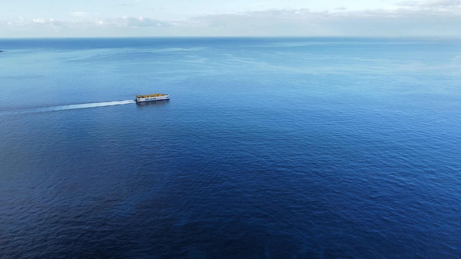 A ship cruises across the vast blue ocean.