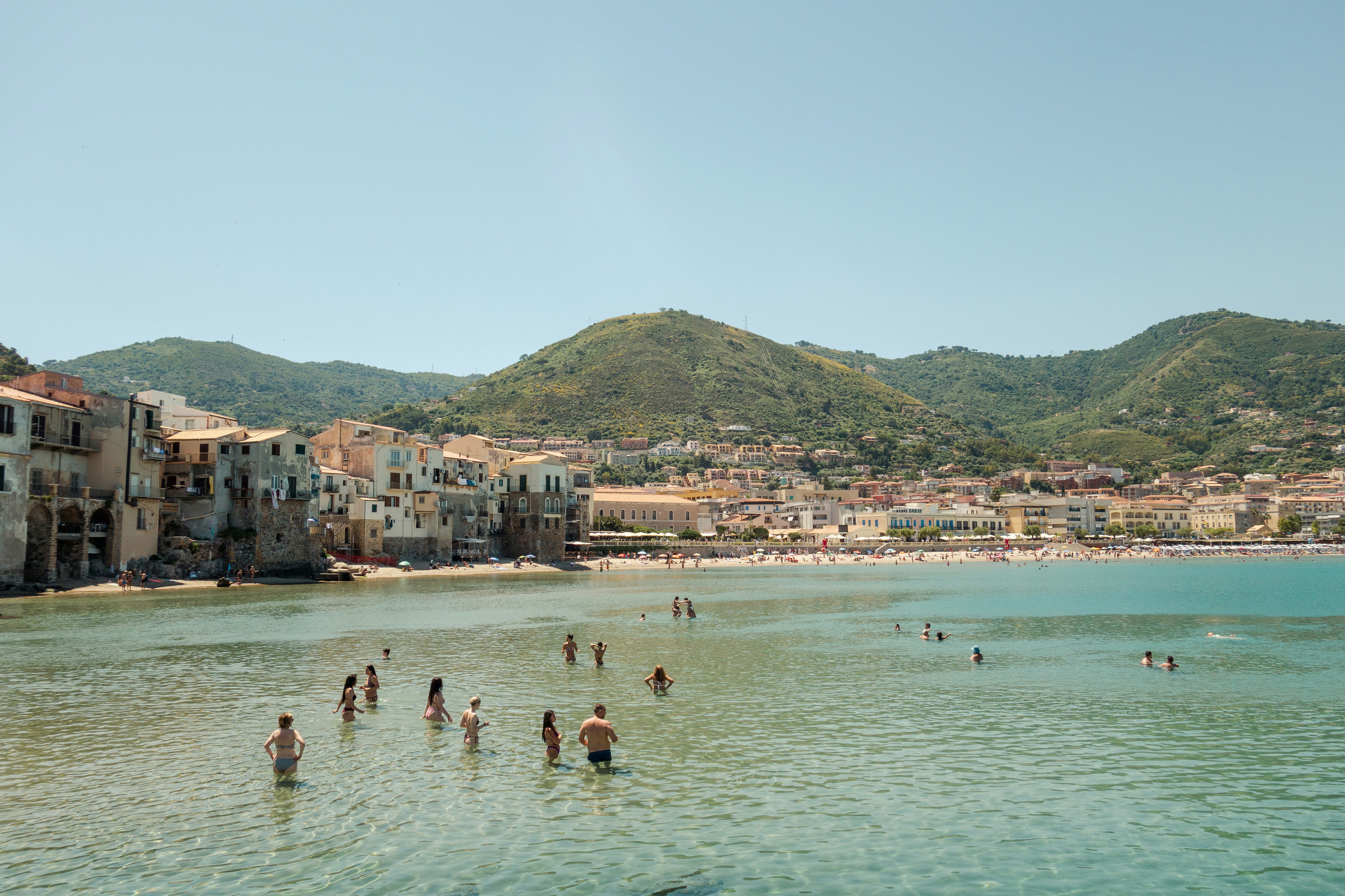People swim in the ocean near a coastal town
