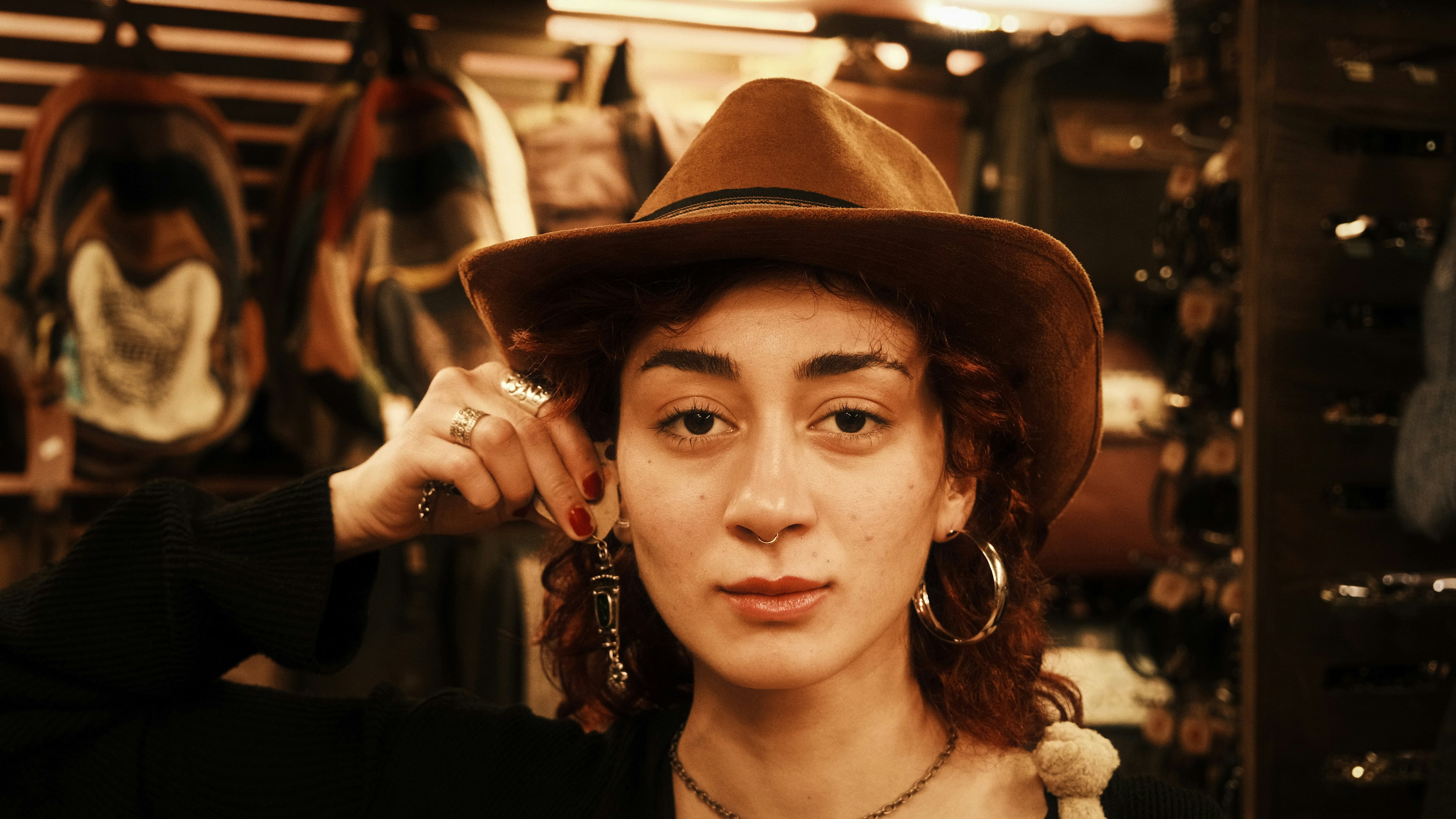 Woman in a hat holding an earring.