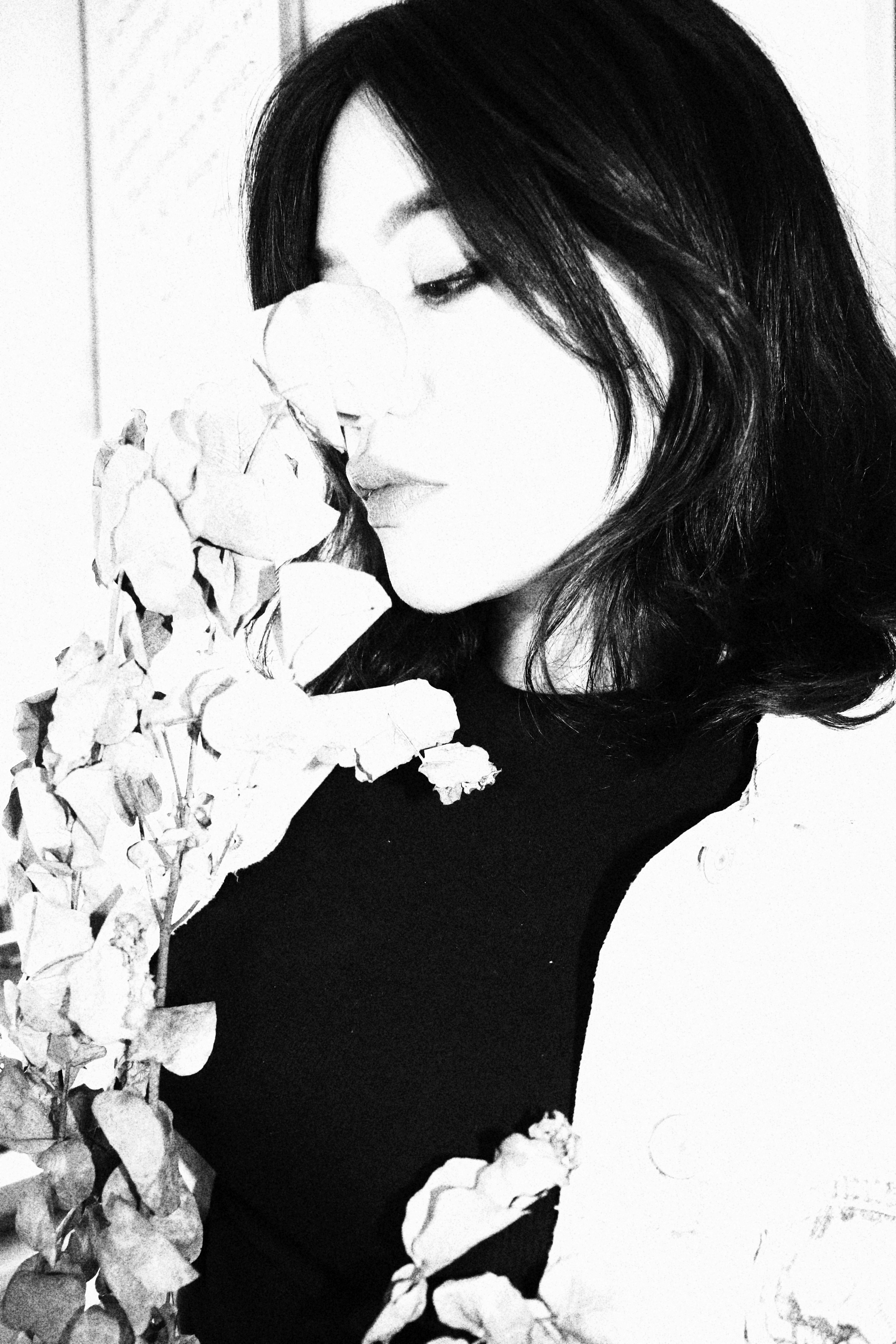Woman smells a rose in a serene black and white photo.
