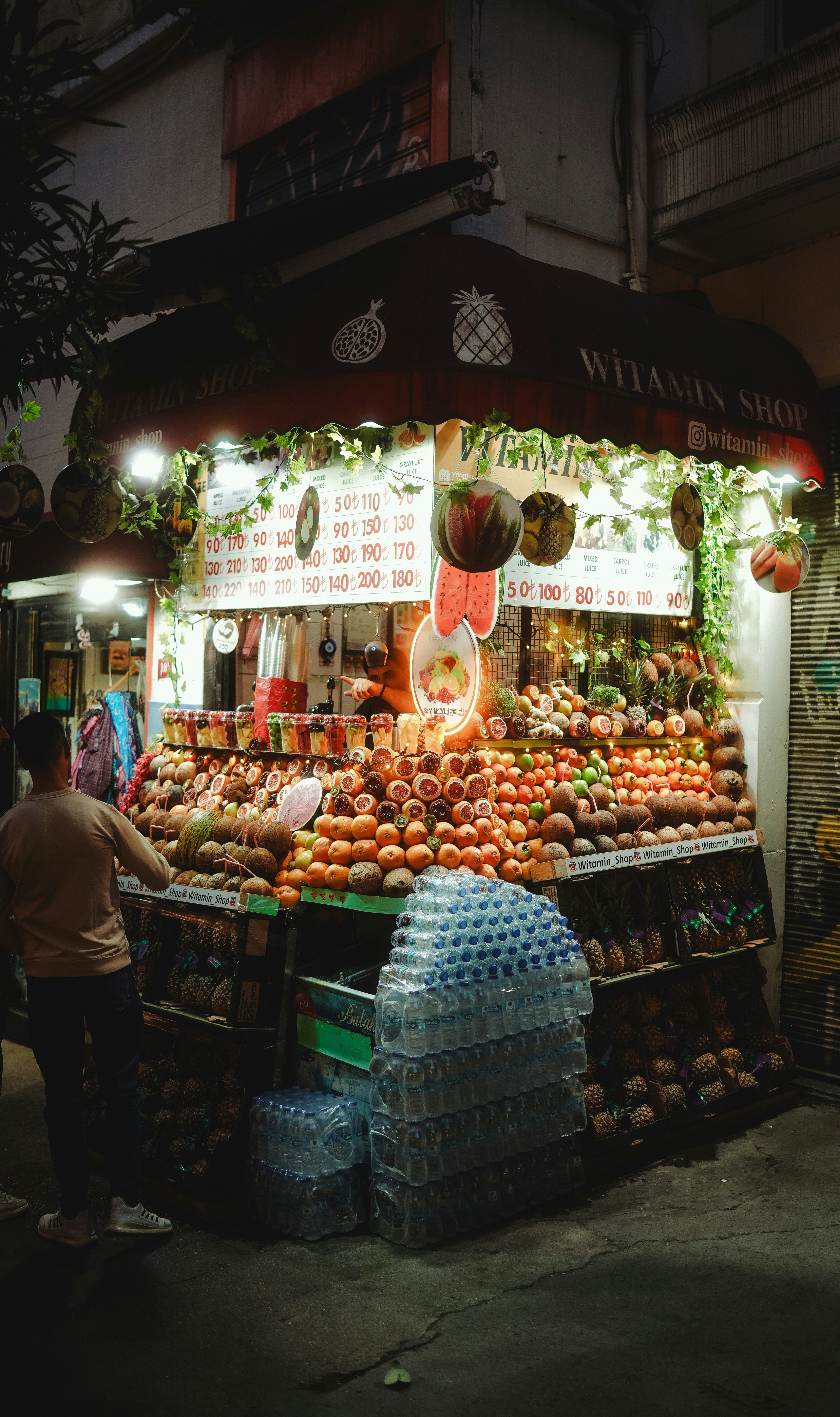 A fruit stand is lit up at night.