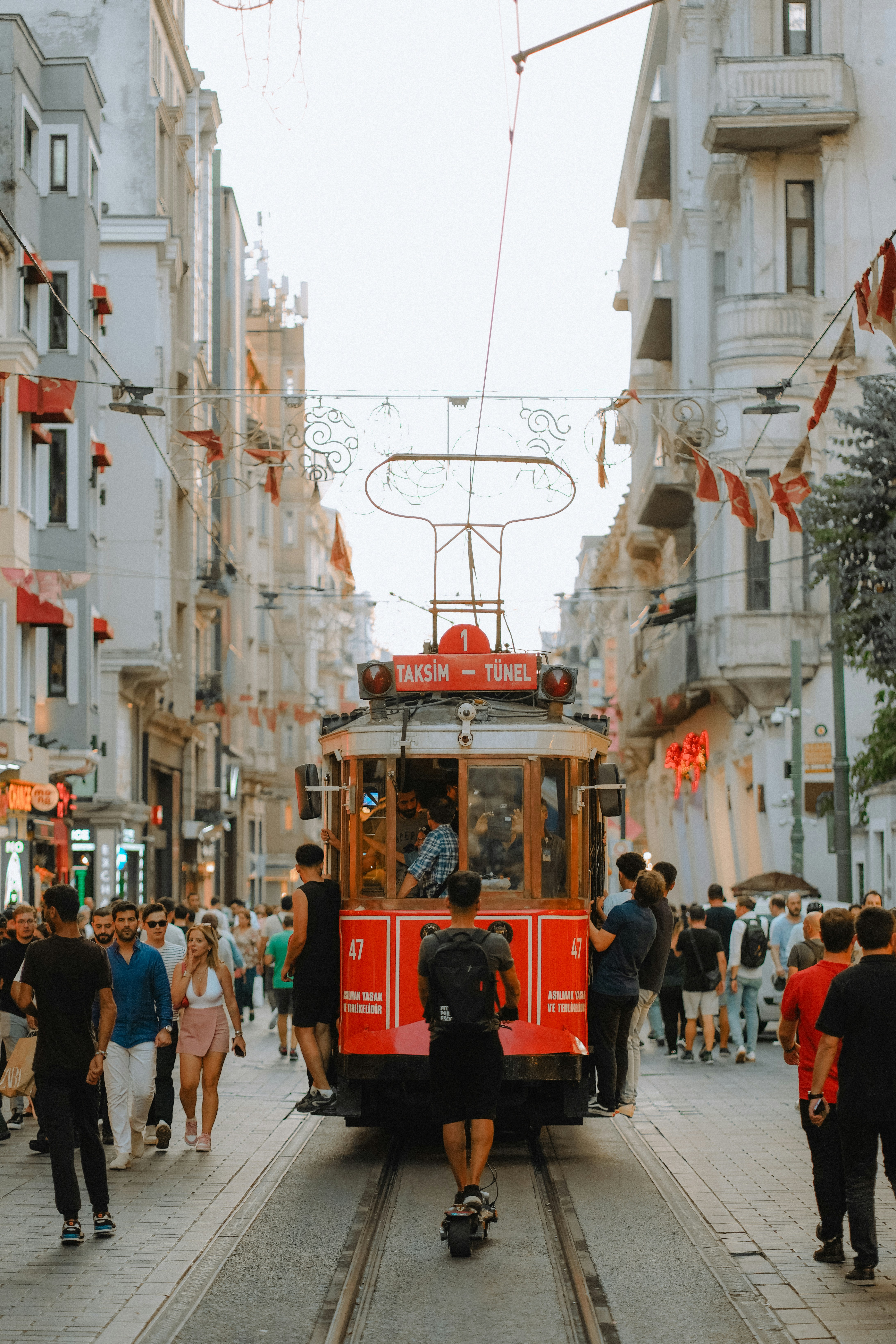 A red tram travels down a busy city street.
