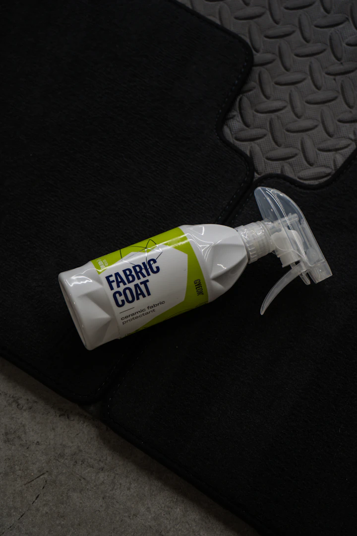 Car care spray bottle placed on a protective car mat