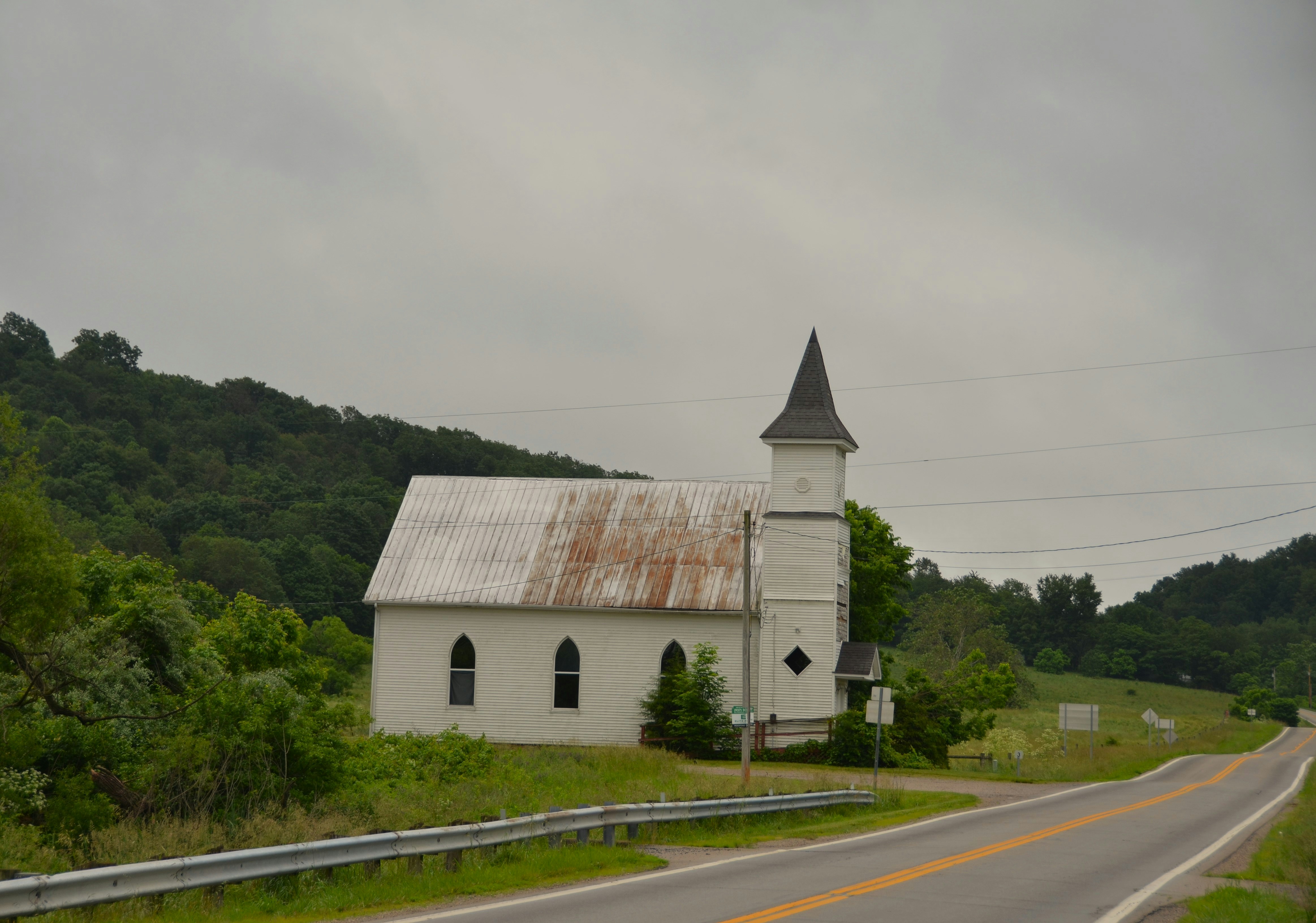 A small, white church stands by a road.
