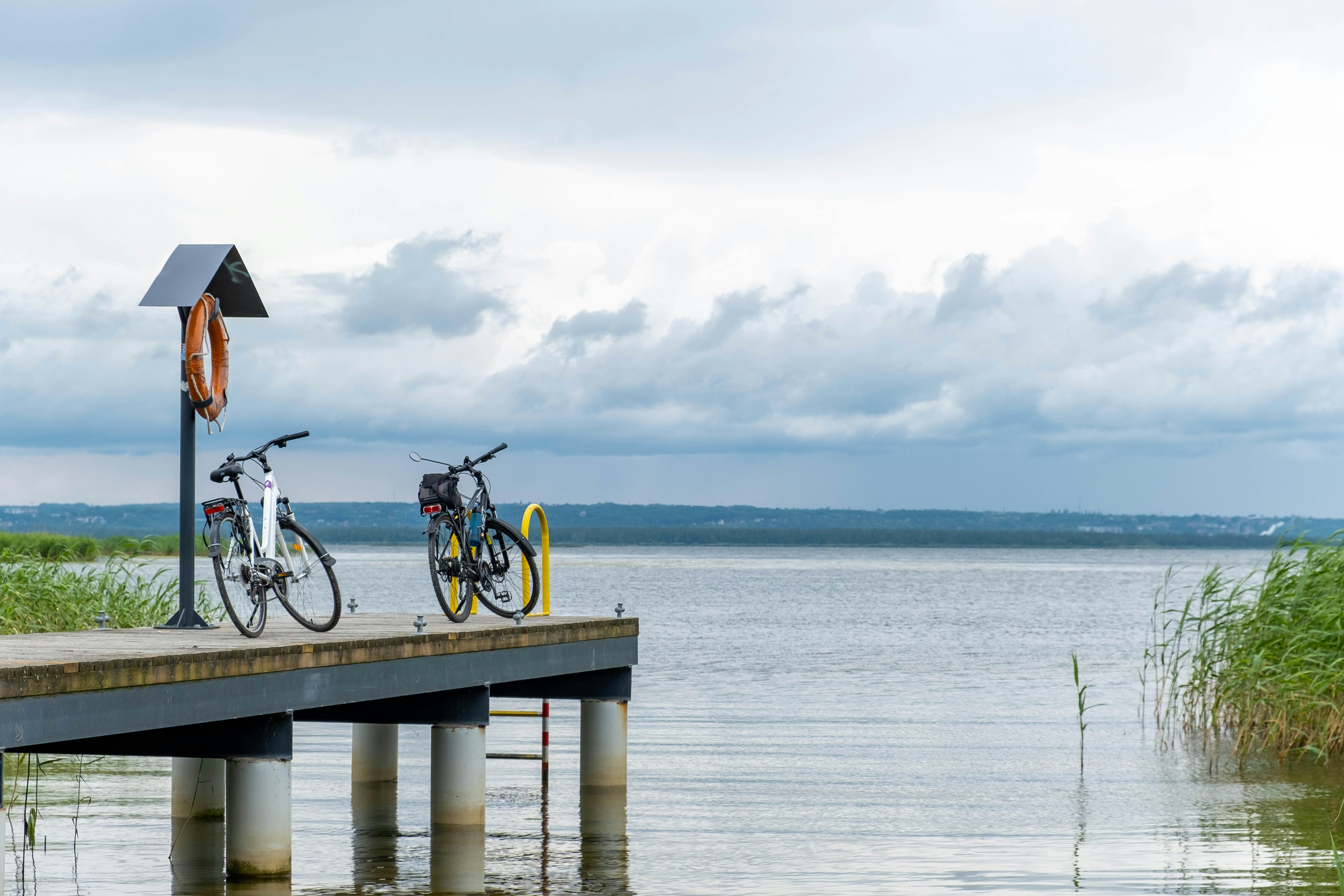 Bikes sit on a dock by the lake.