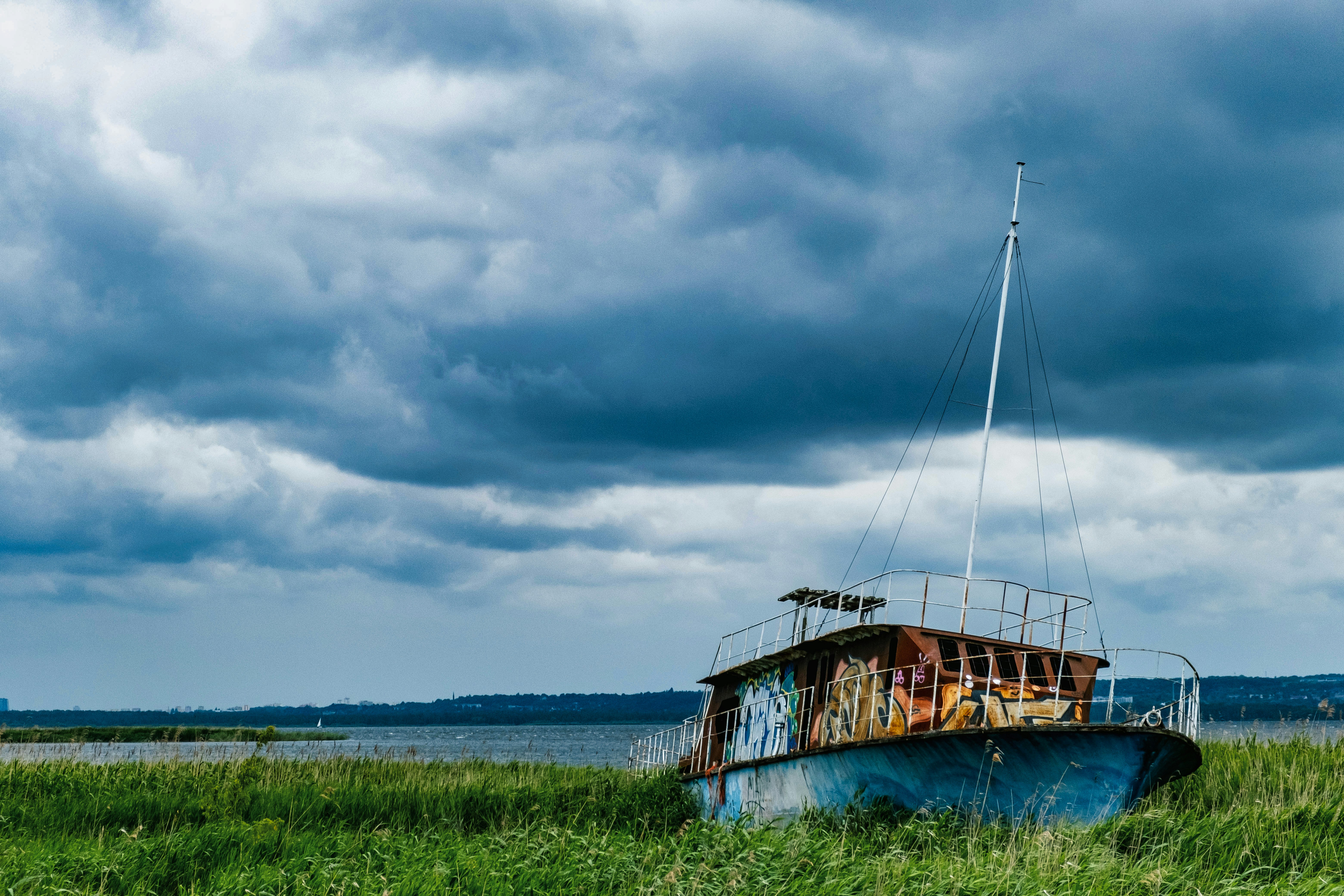 An old, rusty boat sits on grassy shore.