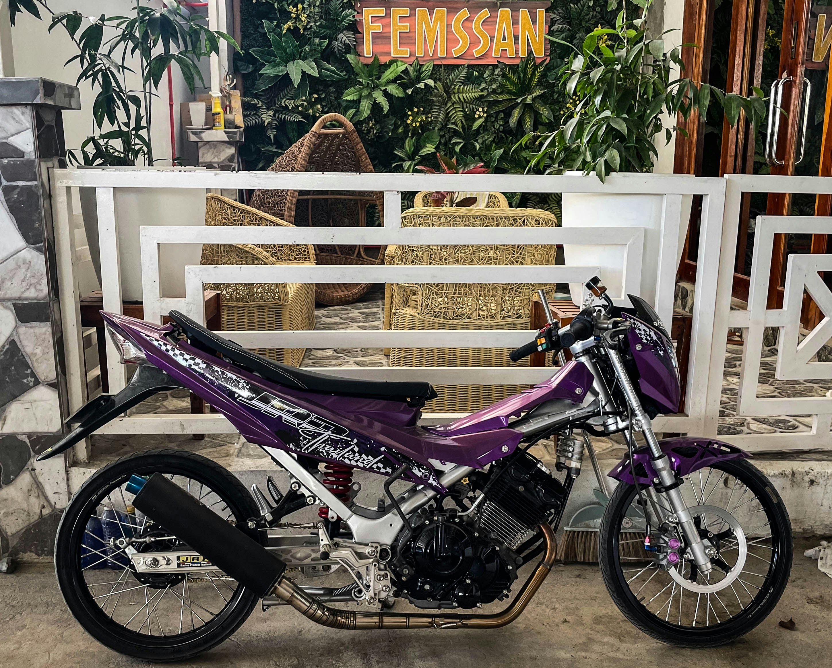 A purple motorcycle stands in front of a building.
