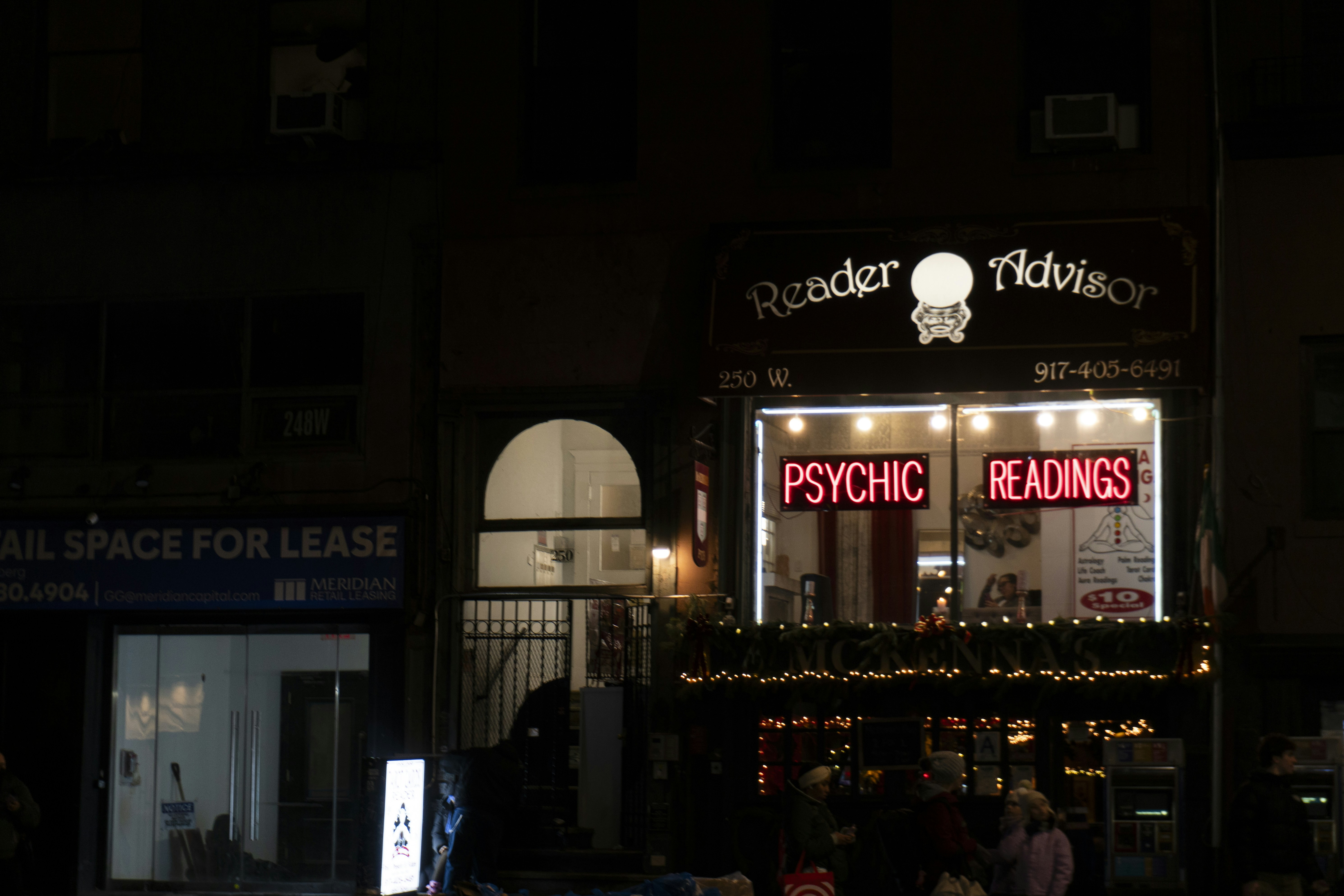 A psychic reading shop glows brightly at night.