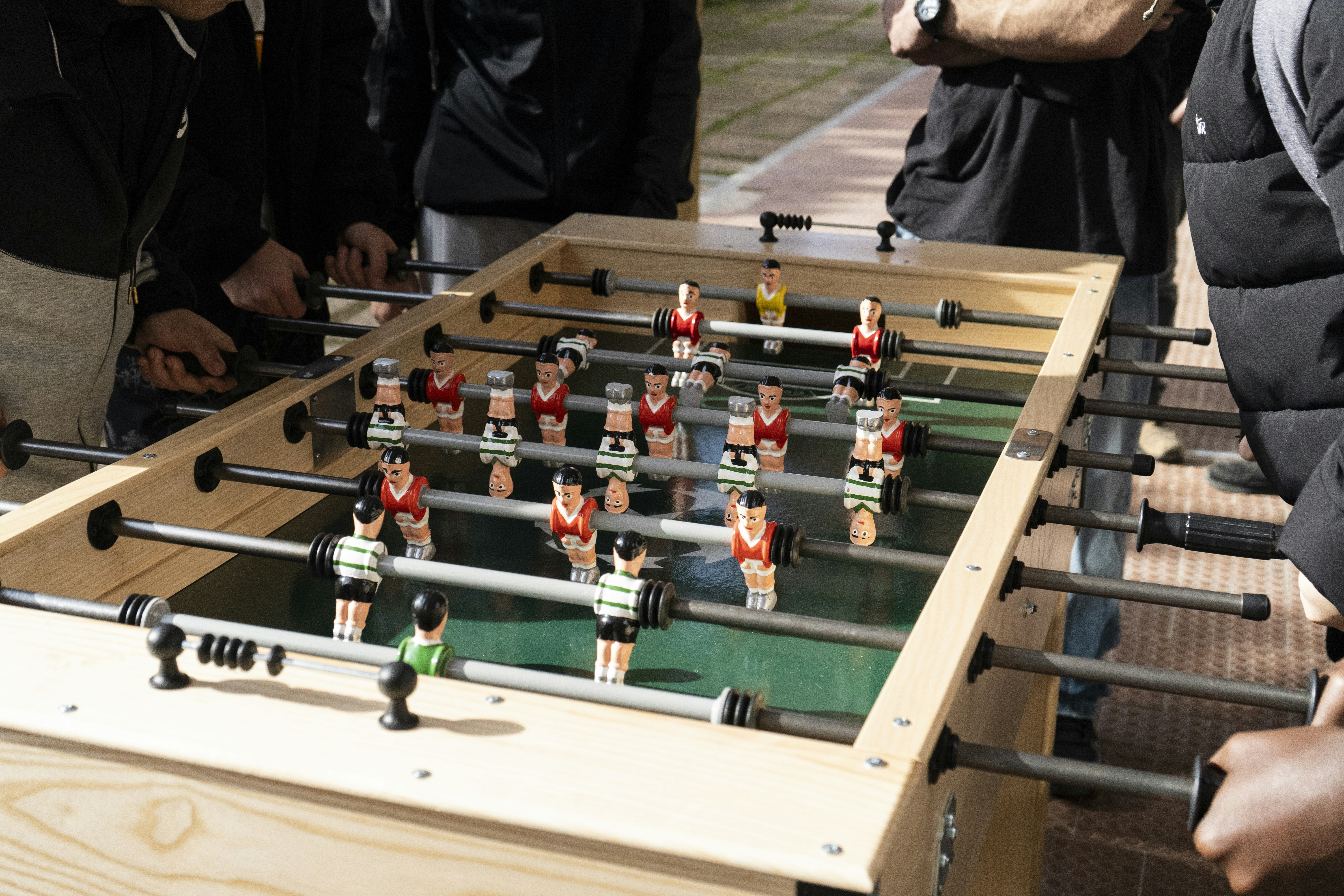 Friends play a casual game of foosball on the sidewalk.
