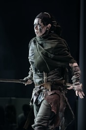 Warrior woman poses with weapons, looking fierce.