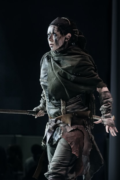 Warrior woman poses with weapons, looking fierce.