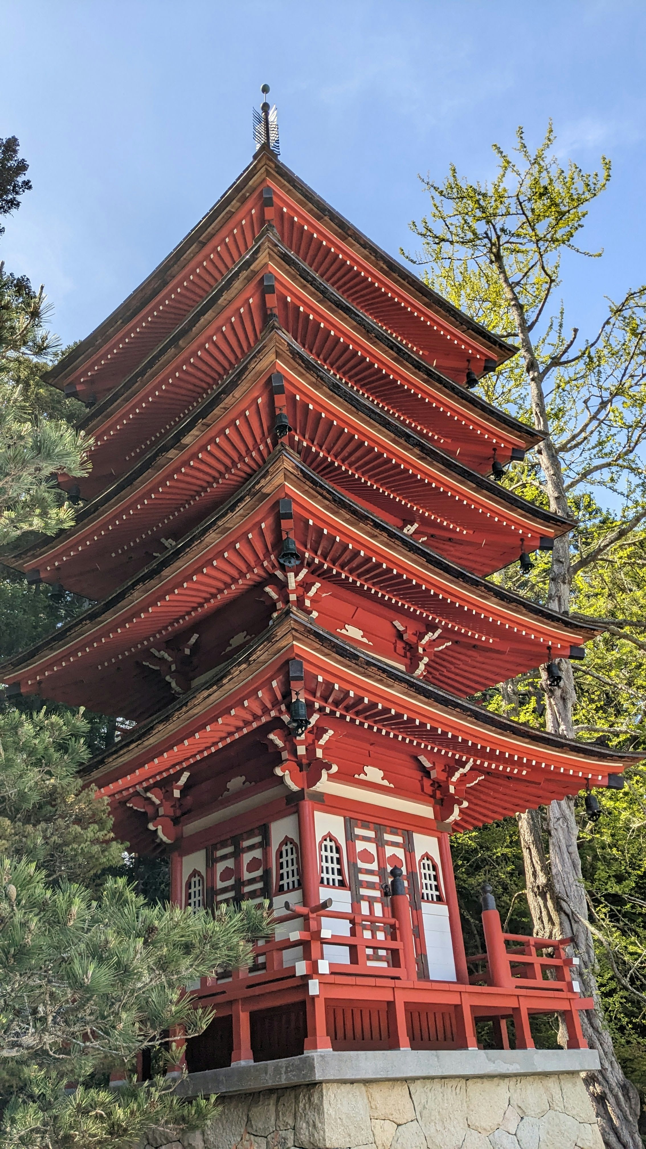 A red pagoda stands tall amidst greenery.