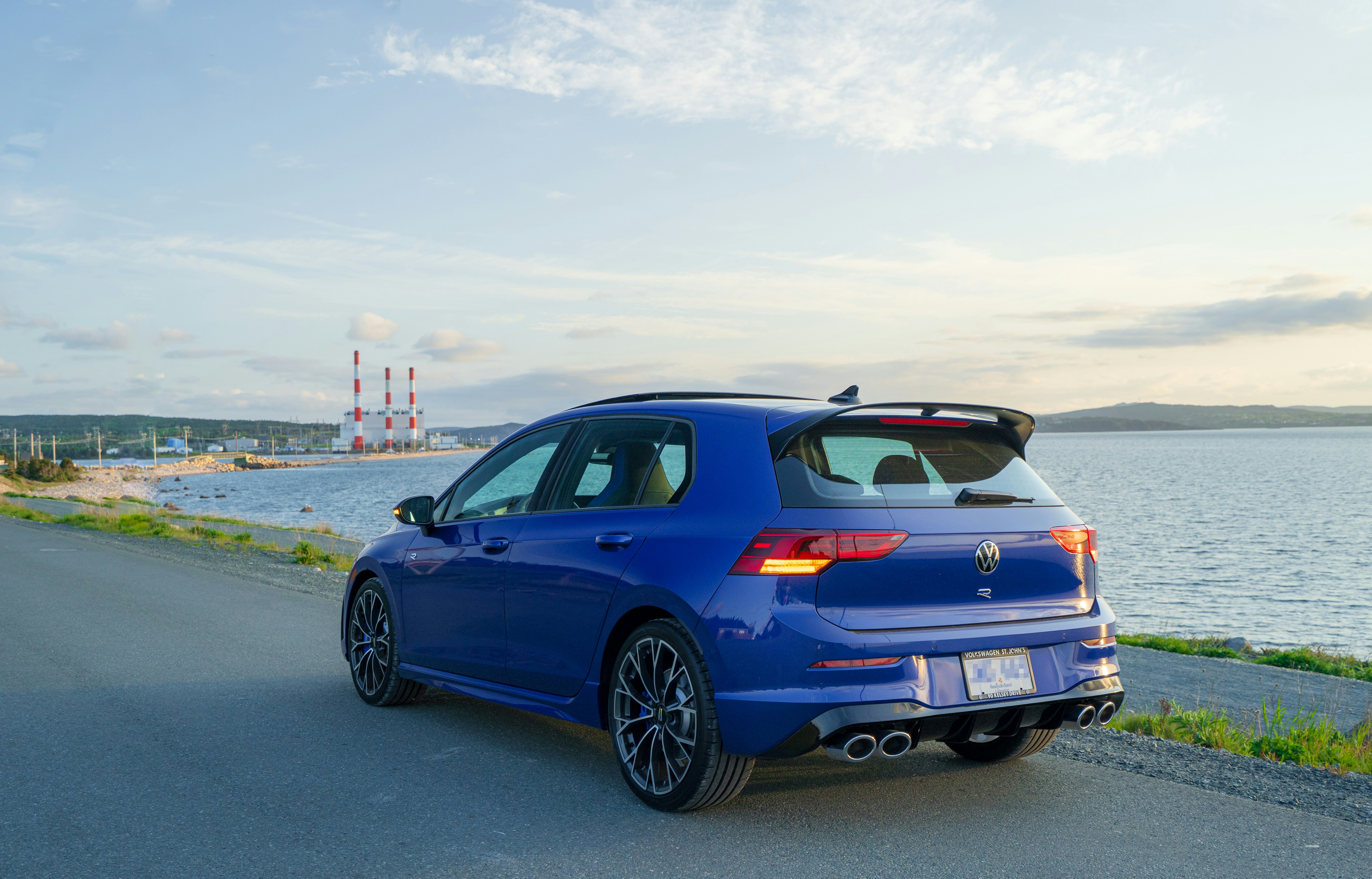 A blue car drives by the coast
