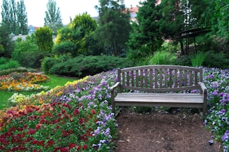 A wooden bench sits in a colorful garden.