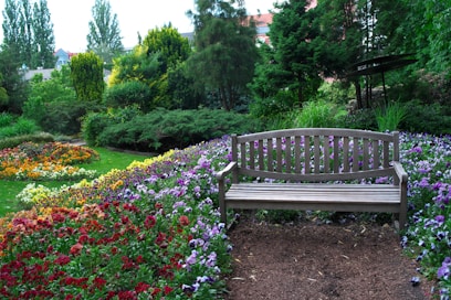 A wooden bench sits in a colorful garden.