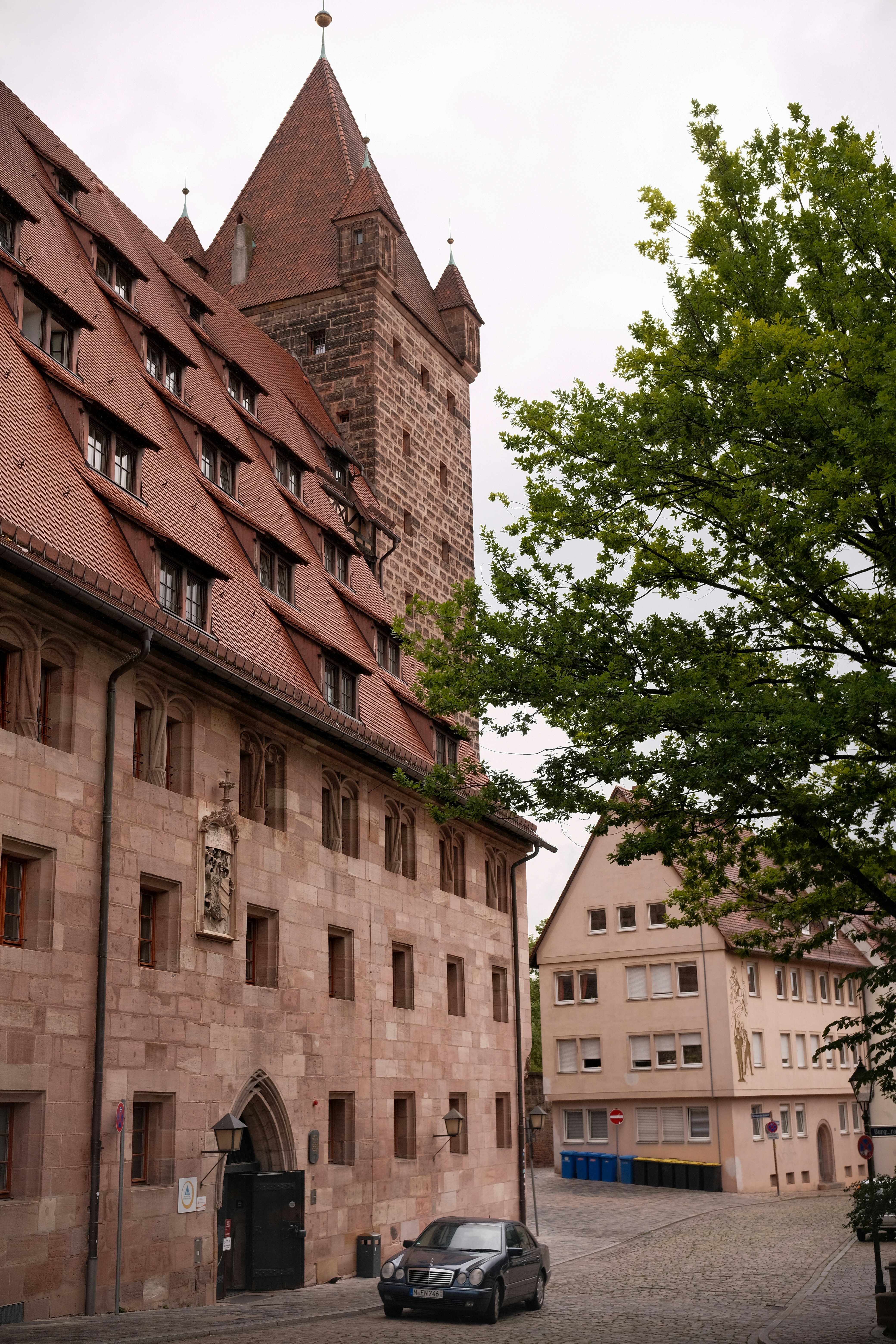 Mercedes-Benz W210 E. Historic stone building with a tower stands beside a cobbled street in Nuremberg on a cloudy day