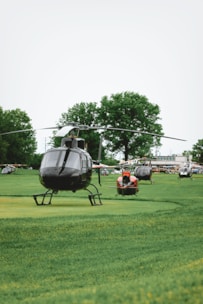 Several helicopters are parked on the green field.