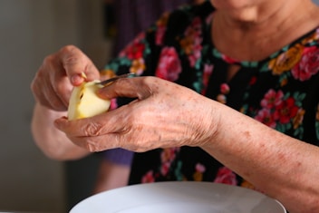 An elderly person peels an apple.