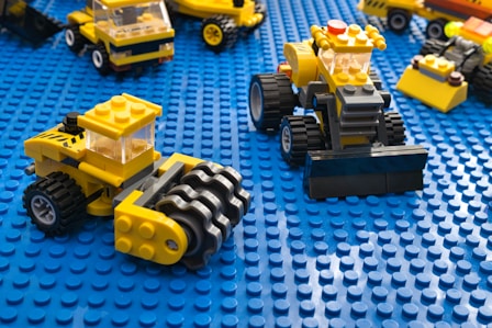 Lego construction vehicles are on a blue surface.