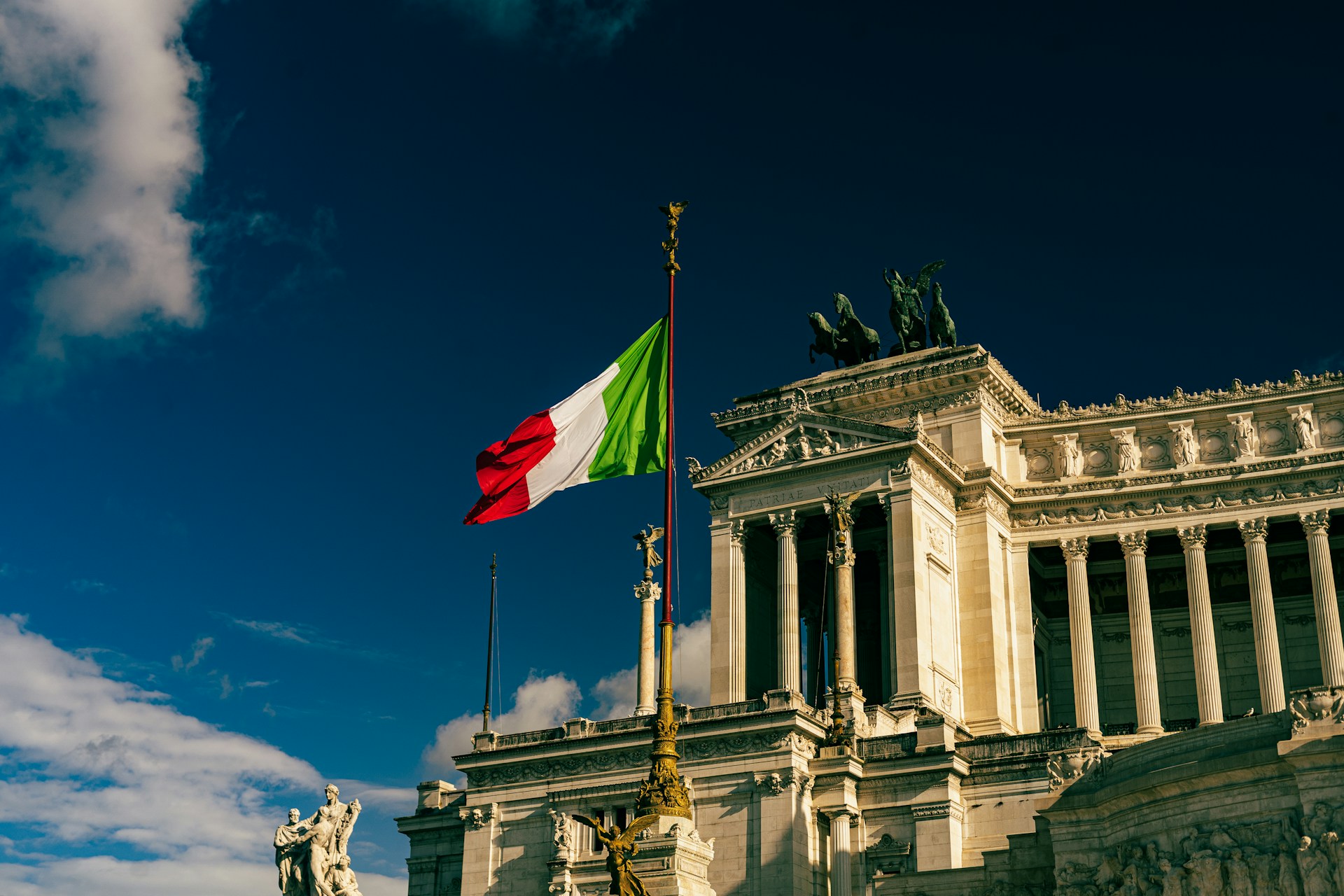 An italian flag flies near an ornate building.